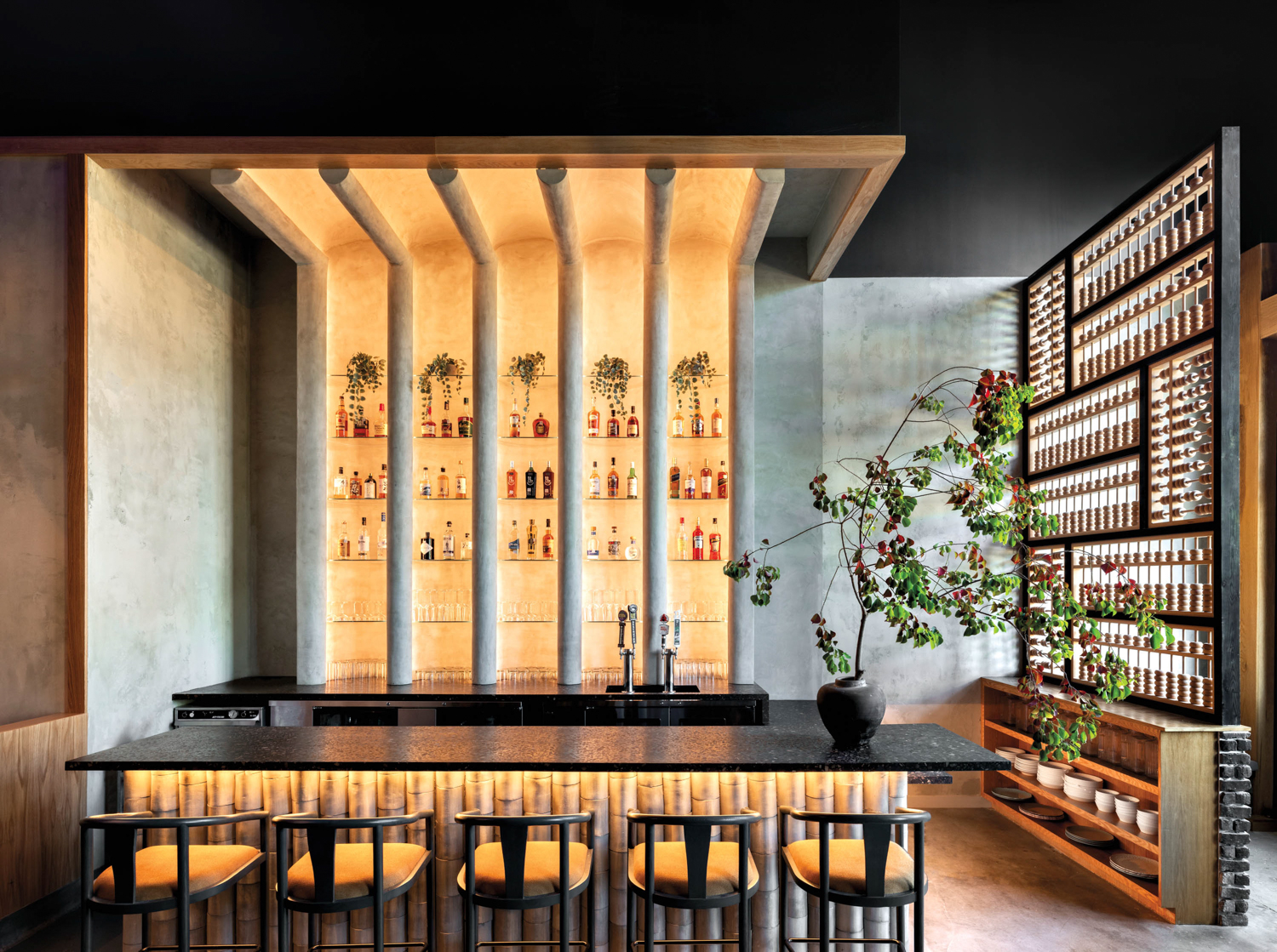 Mala Sichuan Bistro bar with floor-to-ceiling concrete backdrop backlit with warm lights