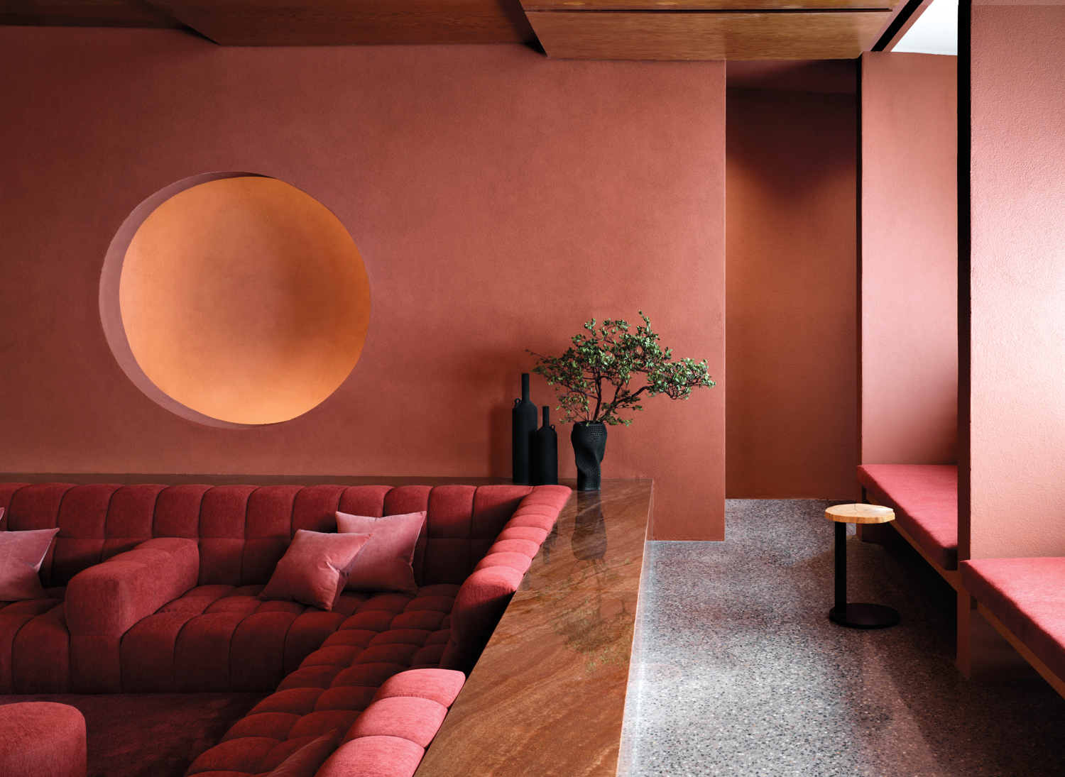 Mii amo lounge area with red walls, a sunken sitting area with a red, tufted sofa and stone accents
