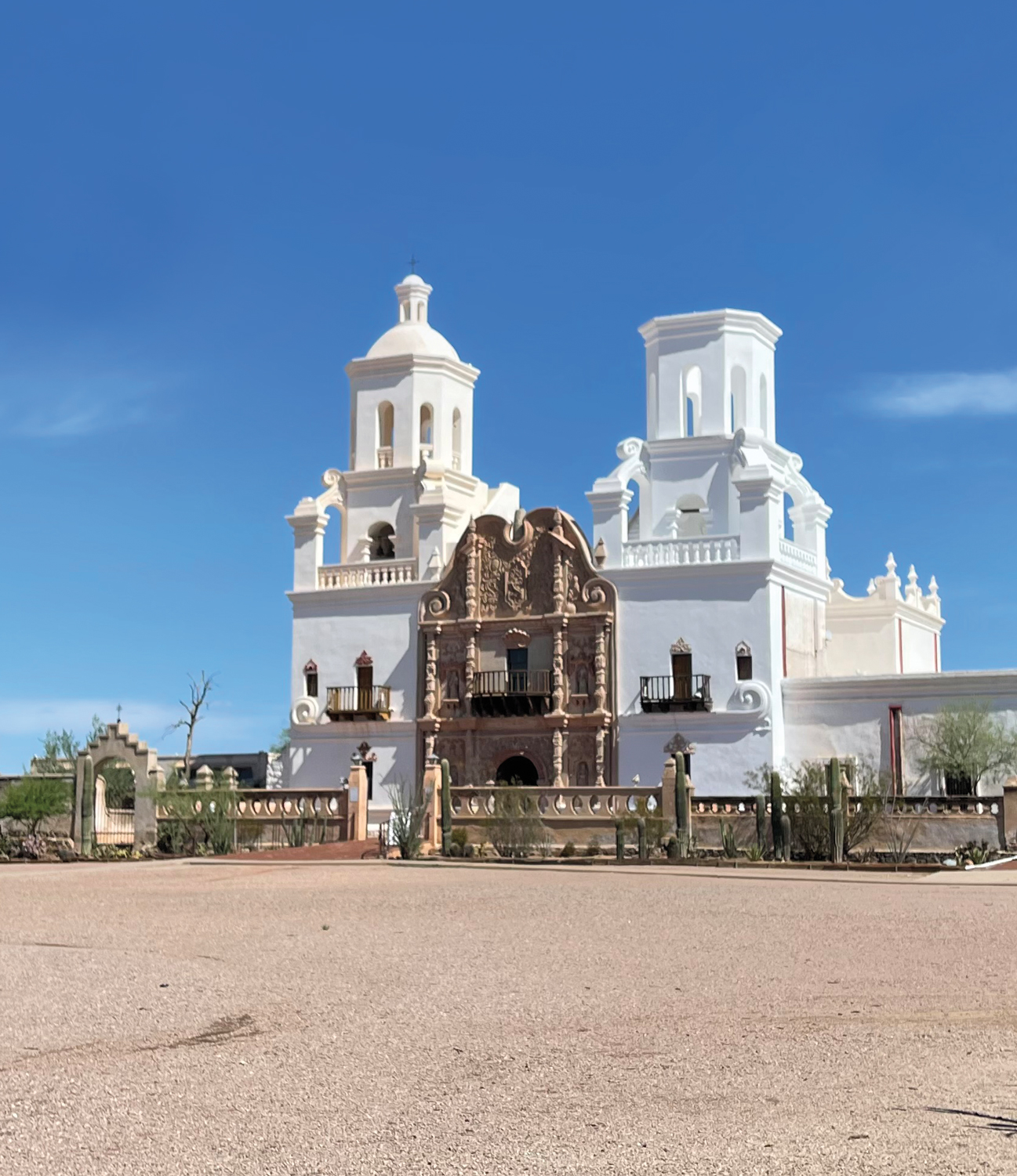 Old Spanish mission with white and brown facade against a clear blue sky, suggested by Arizona design pros