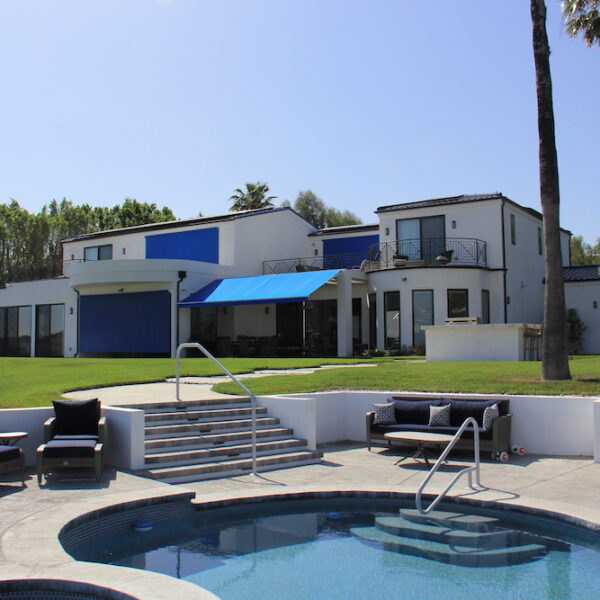 exterior of a modern white home with solar screens, retractable awnings and round pool