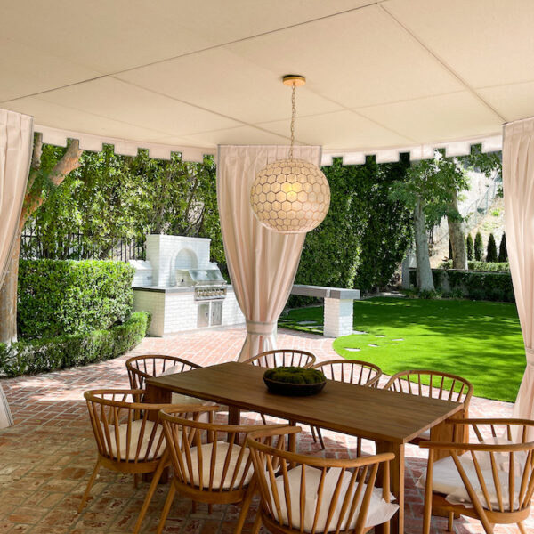 wood table and chairs under a curved patio with canopy and drapes