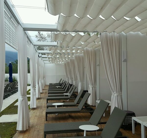 white awnings and drapes on patio with lounge chairs