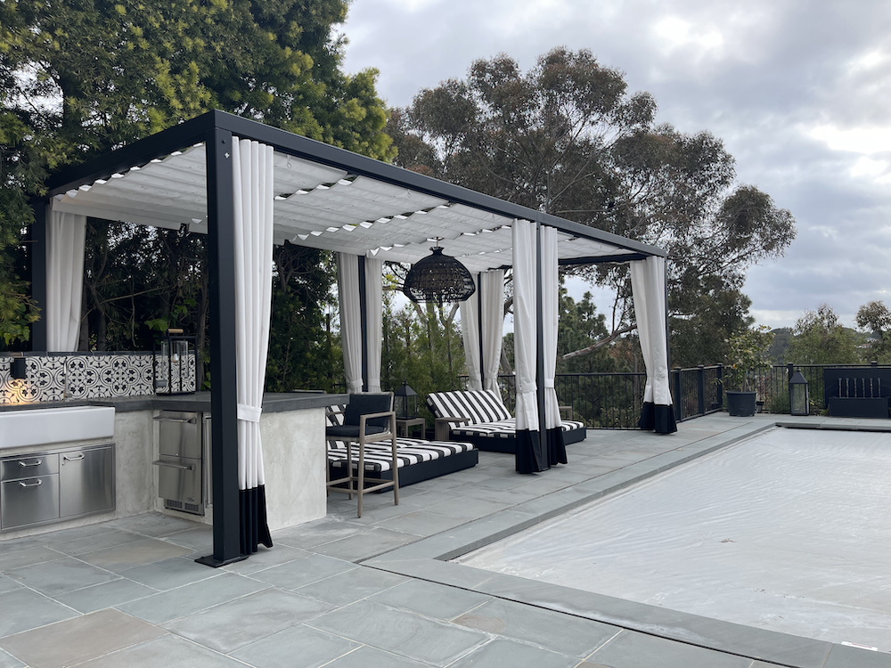 black and white outdoor furniture on patio under a wire shade structure with white drapes