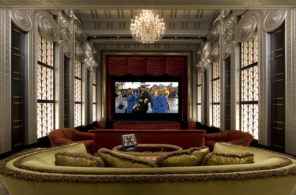 opulent home theater with chandelier and red and gold couches