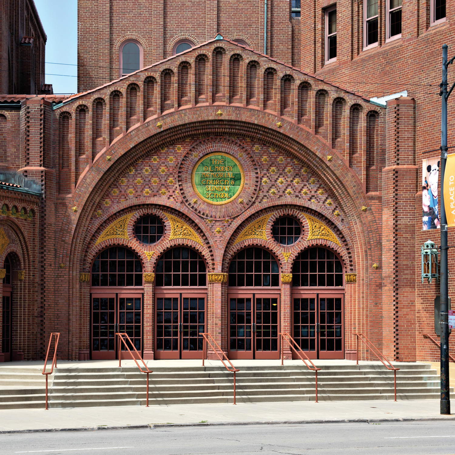 Church featuring arched entryways and terra cotta brick facade with yellow and green accents