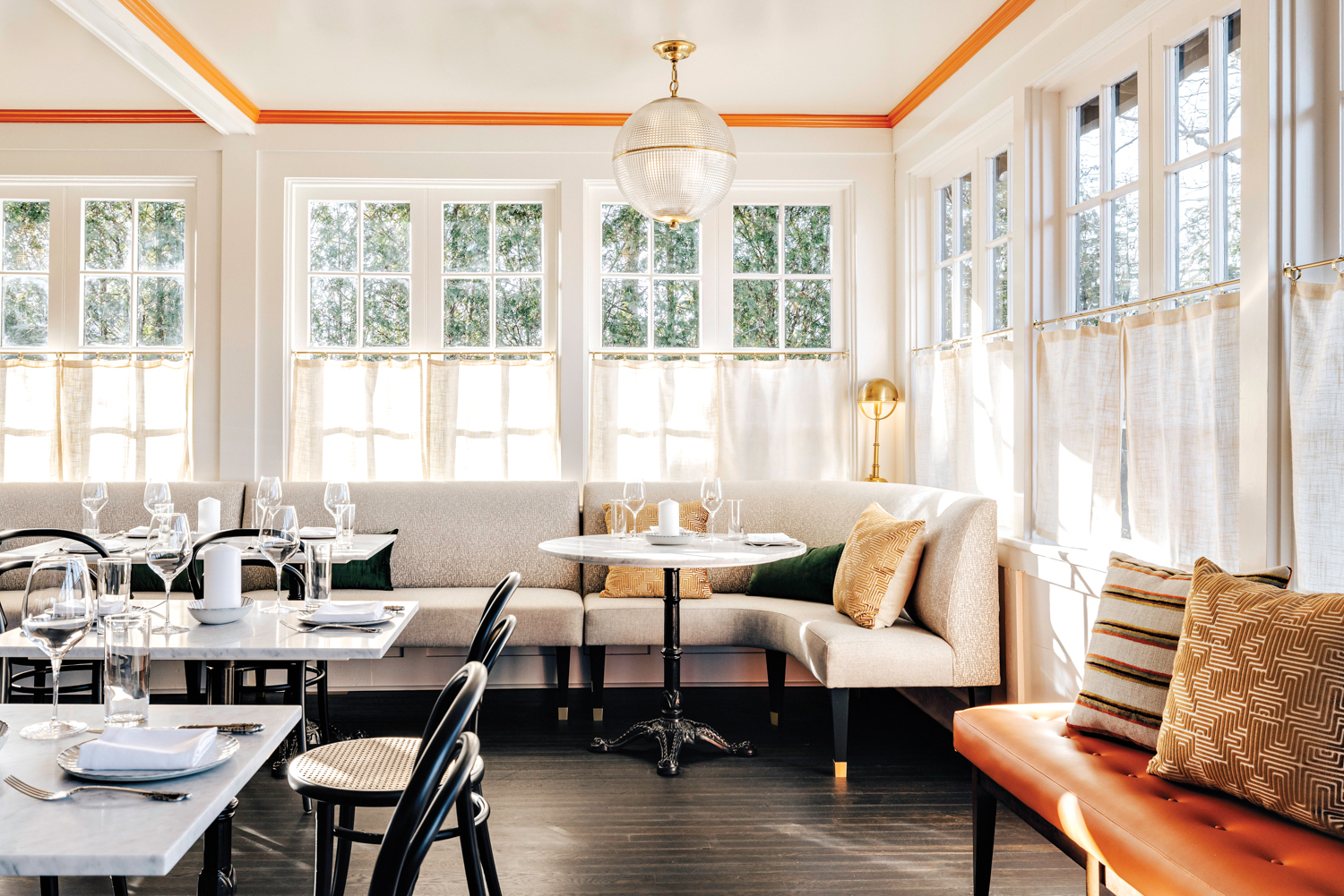 French restaurant Enchanté with window-clad dining room and orange accents