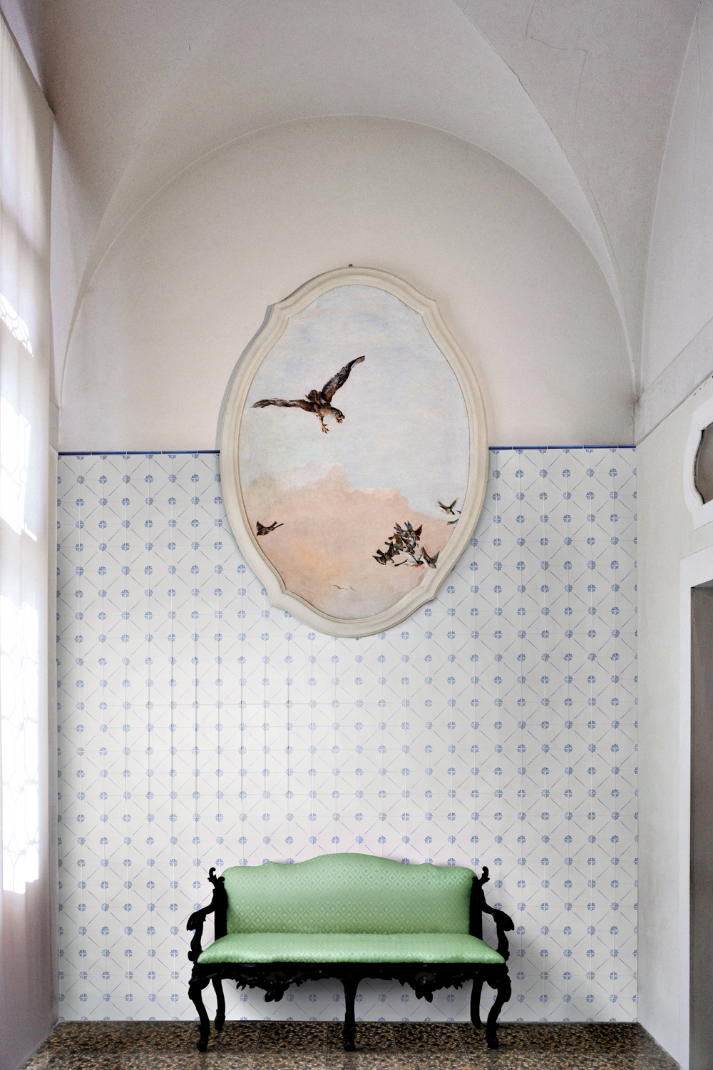 Blue and white tiled wall with oval framed artwork of birds and green bench