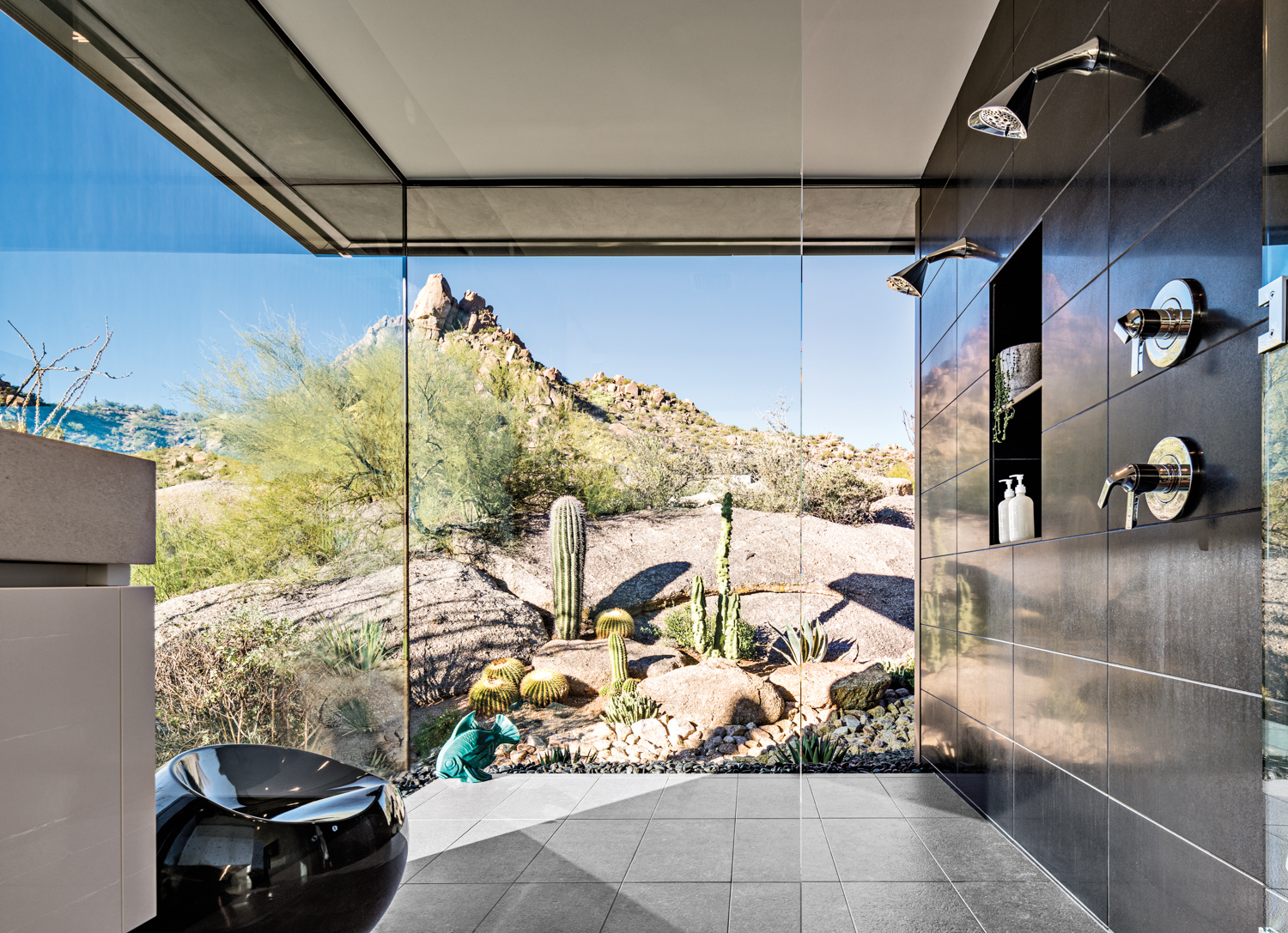 Black granite dual shower with two glass walls looking out on the desert