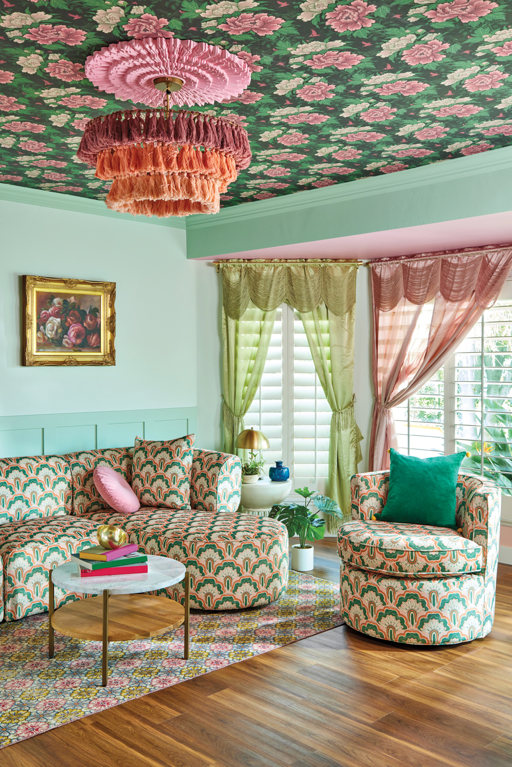 Living room with mint walls, pattered furniture, fringed orange chandelier and pink and green drapes