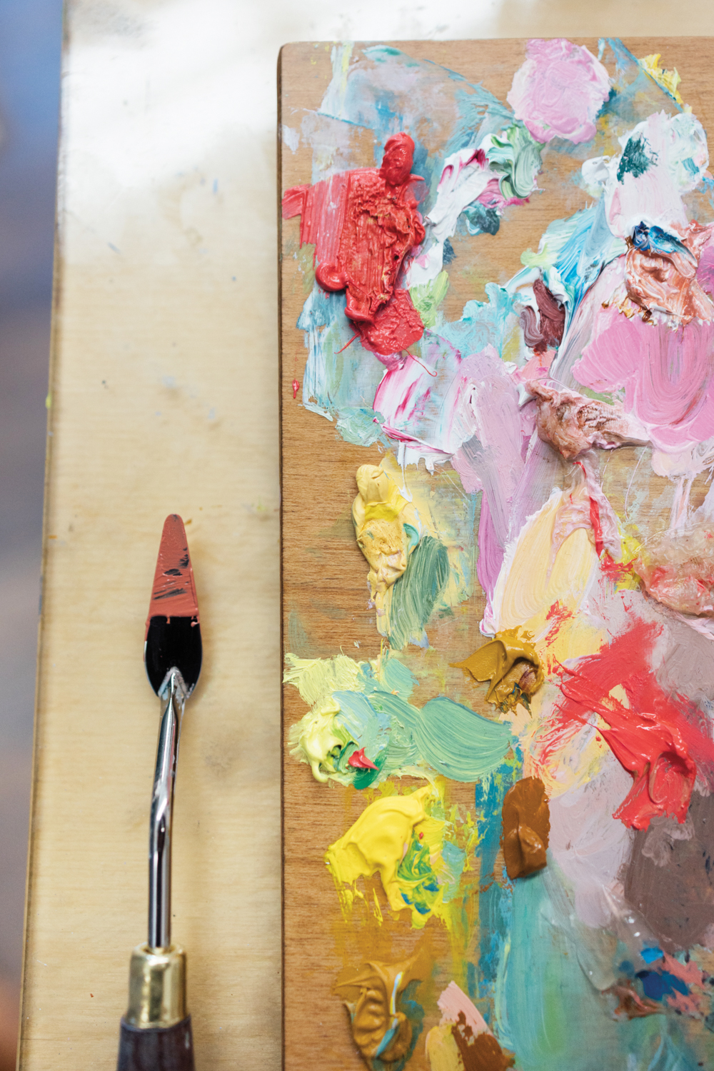 a palette of paint with a palette knife next to it
