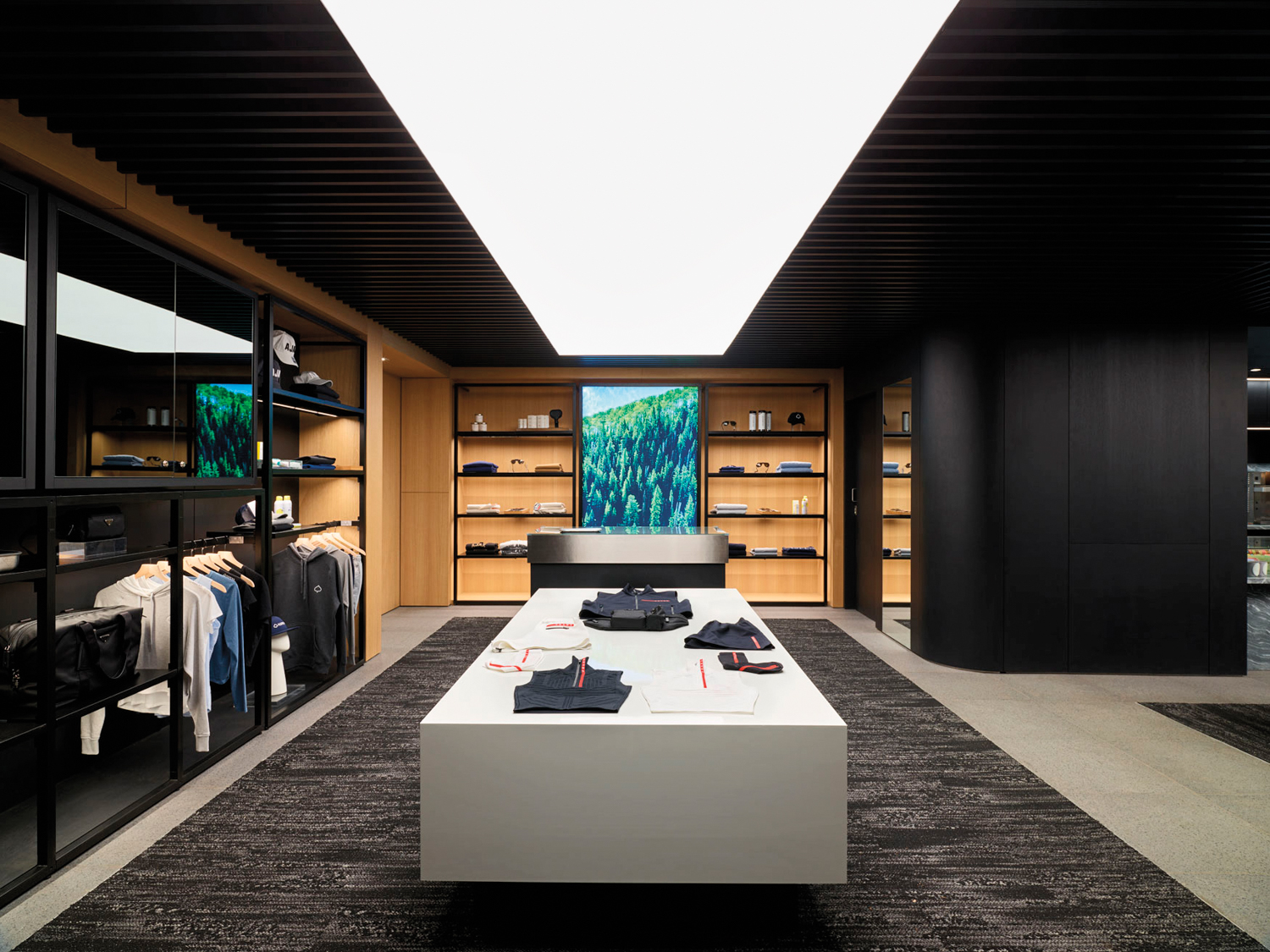 Interior of AspenX store with a dark-gray rug, white Island with clothes on display and shelving
