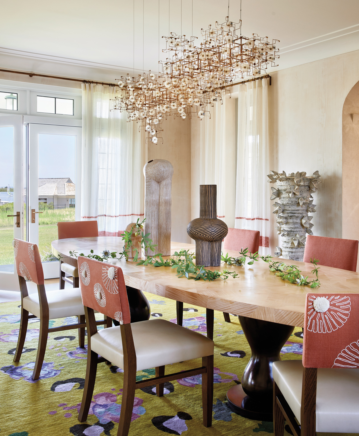 dining room with ovular dining table, yellow floral rug and red and white chairs by Ellen Hamilton