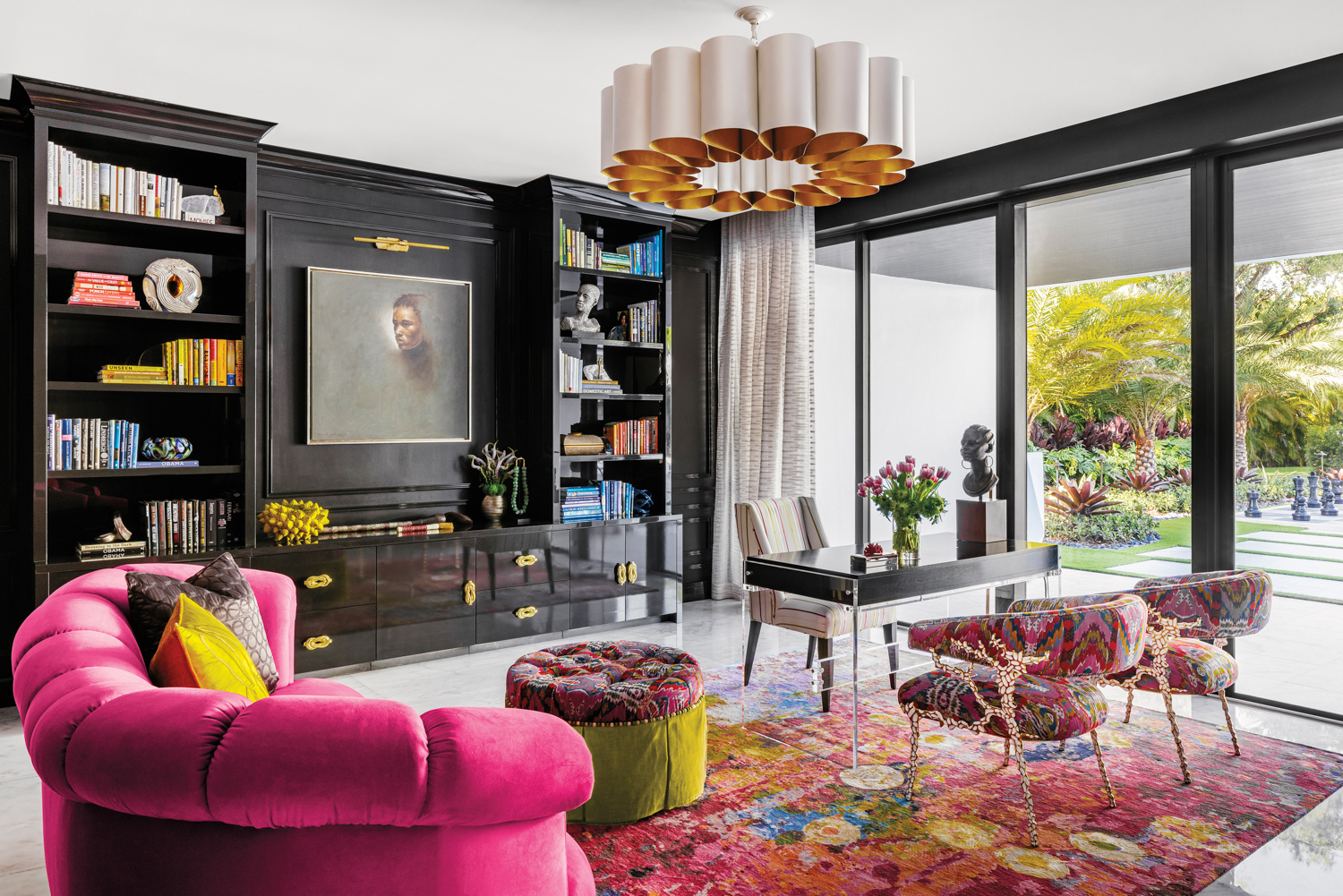 office with pink velvet sofa, black cabinetry, round pendant and patterned rug and armchairs
