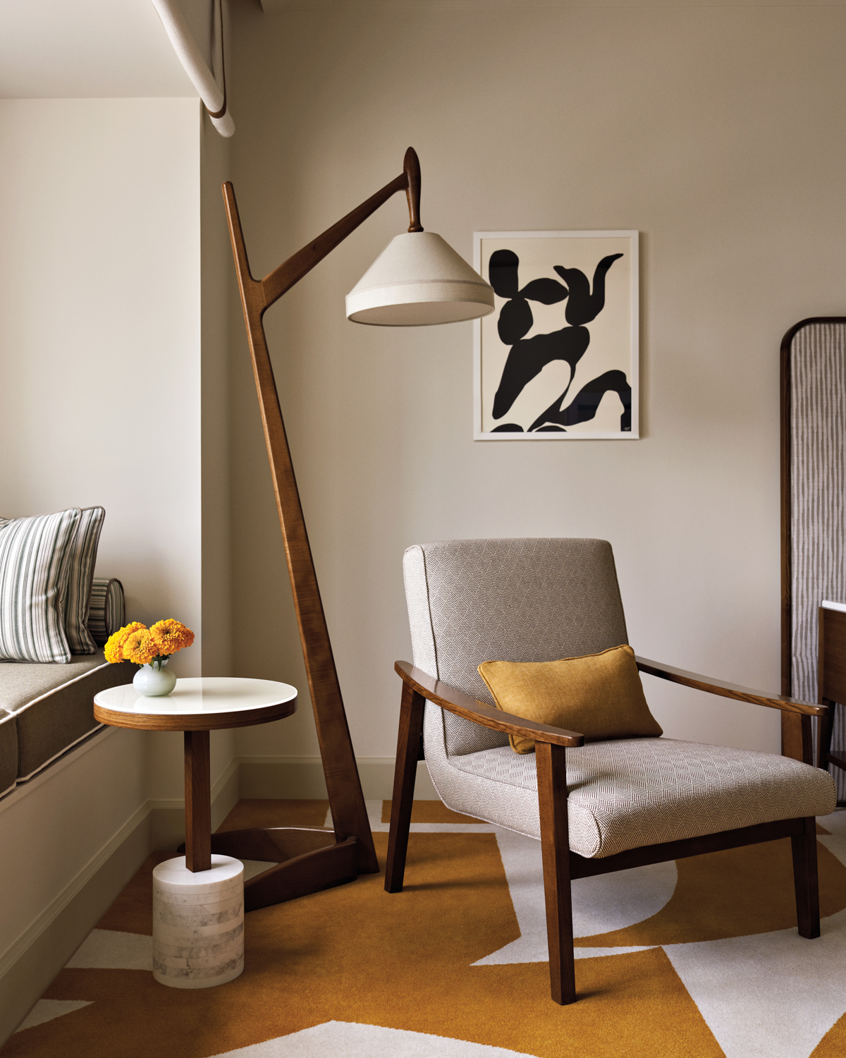 Midcentury-style armchair, floor lamp and side table sit atop yellow-and-white carpet