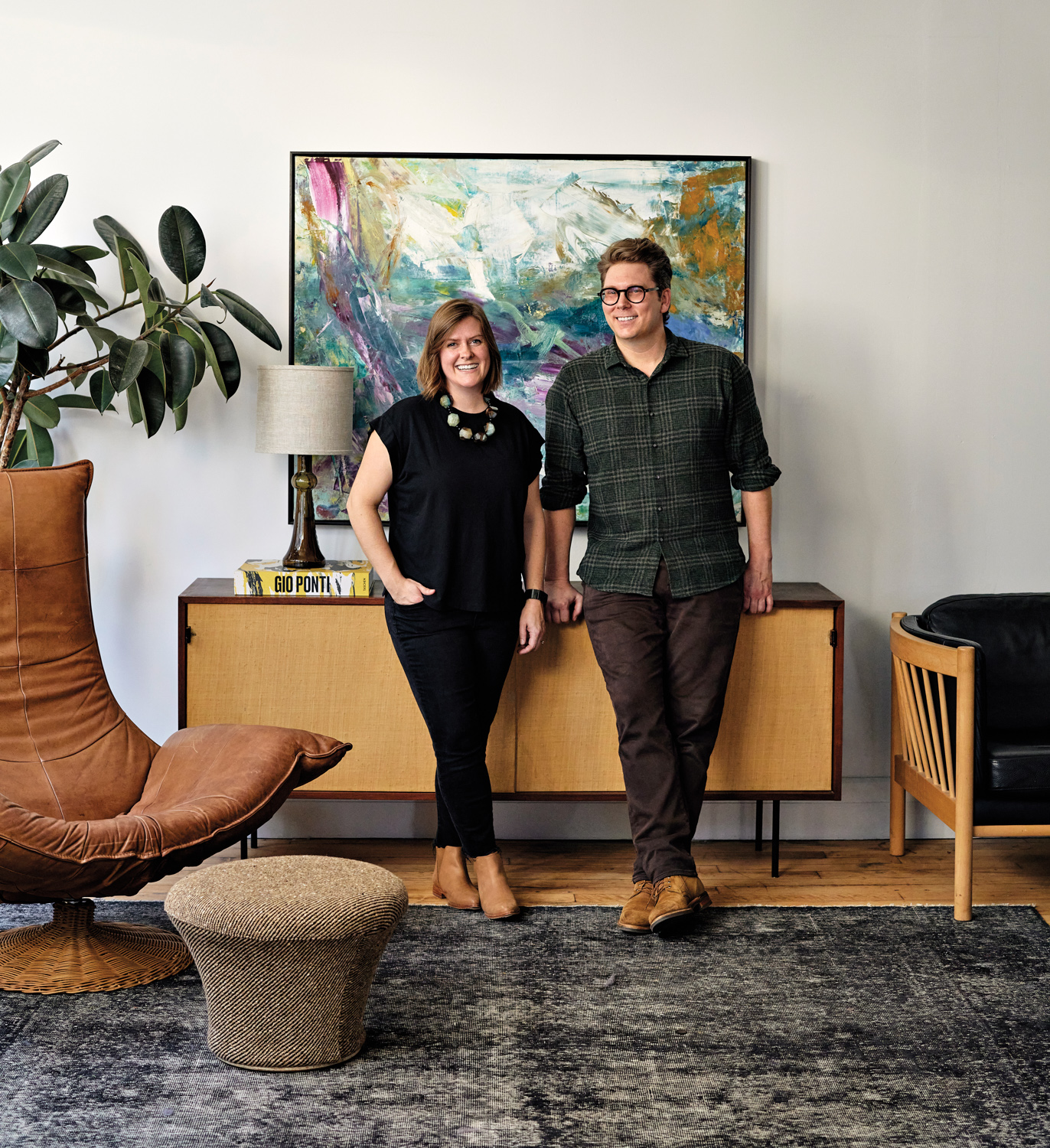 Megan Prime and Joe McGuire standing in front of a console, artwork, and leather lounge chair