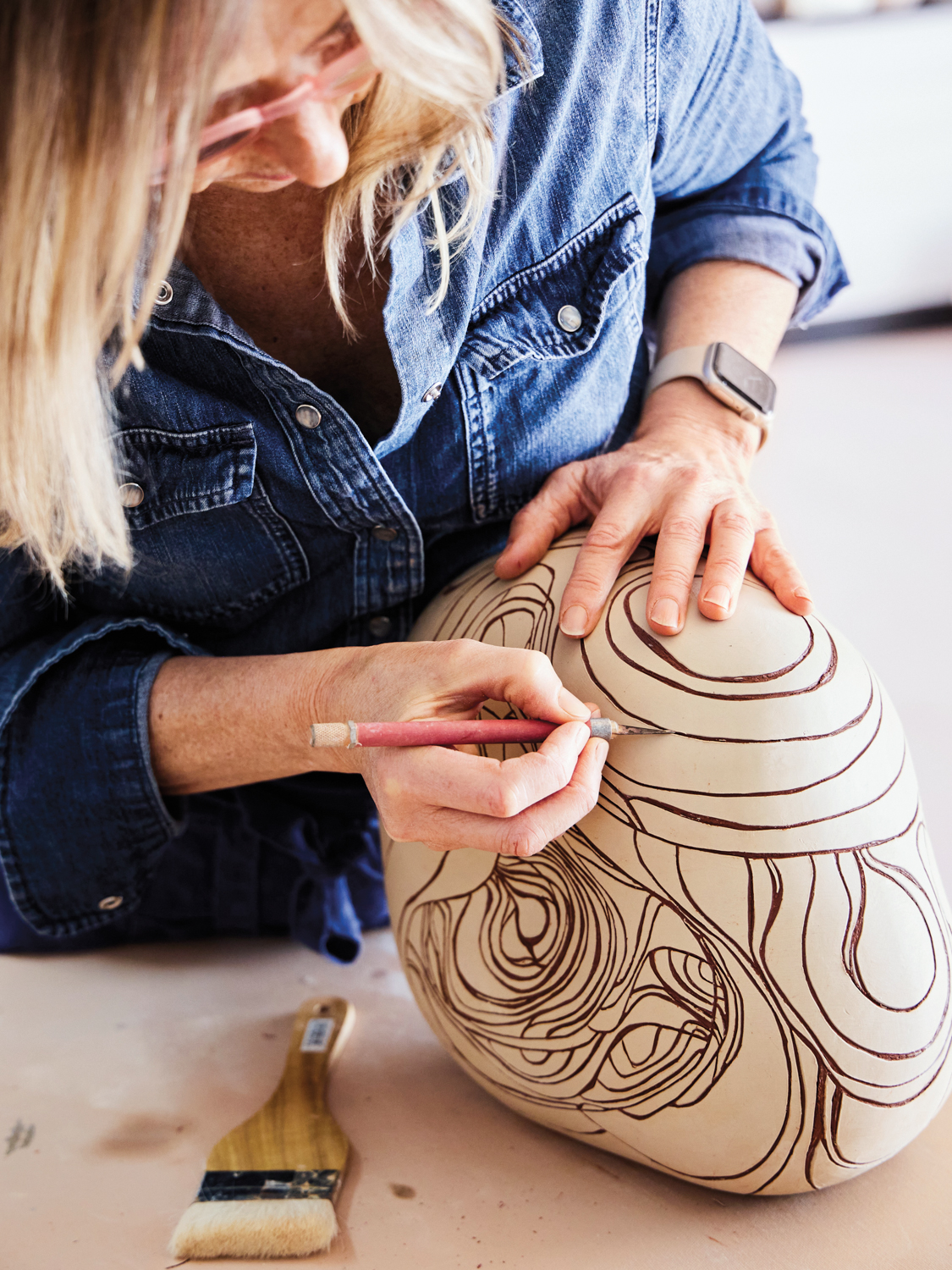Woman carving details onto a clay vessel