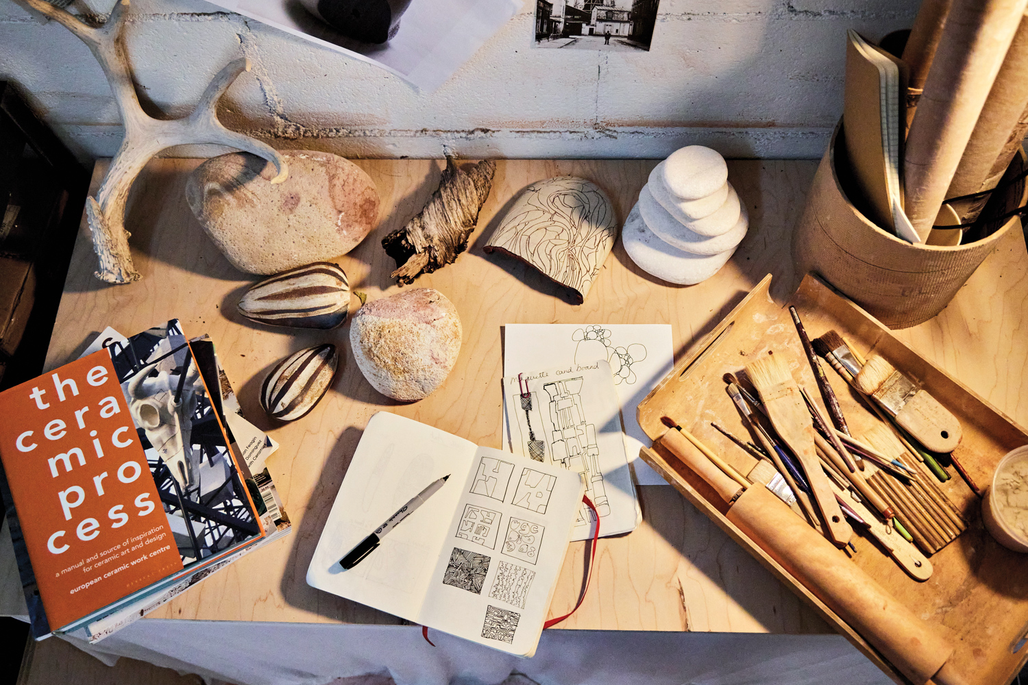 Table with objects, notebooks, inspiration clippings and tools