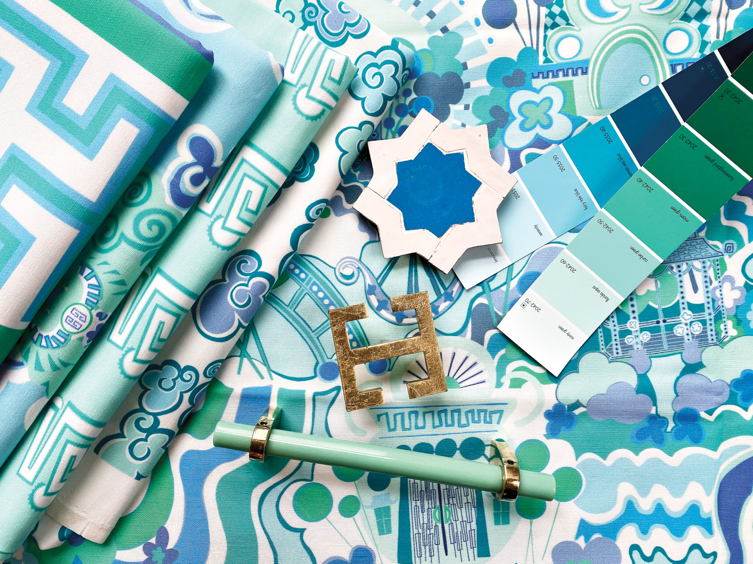 Vibrant blue-and-green patterned textiles layered with paint chips, tiles and accent pulls on top