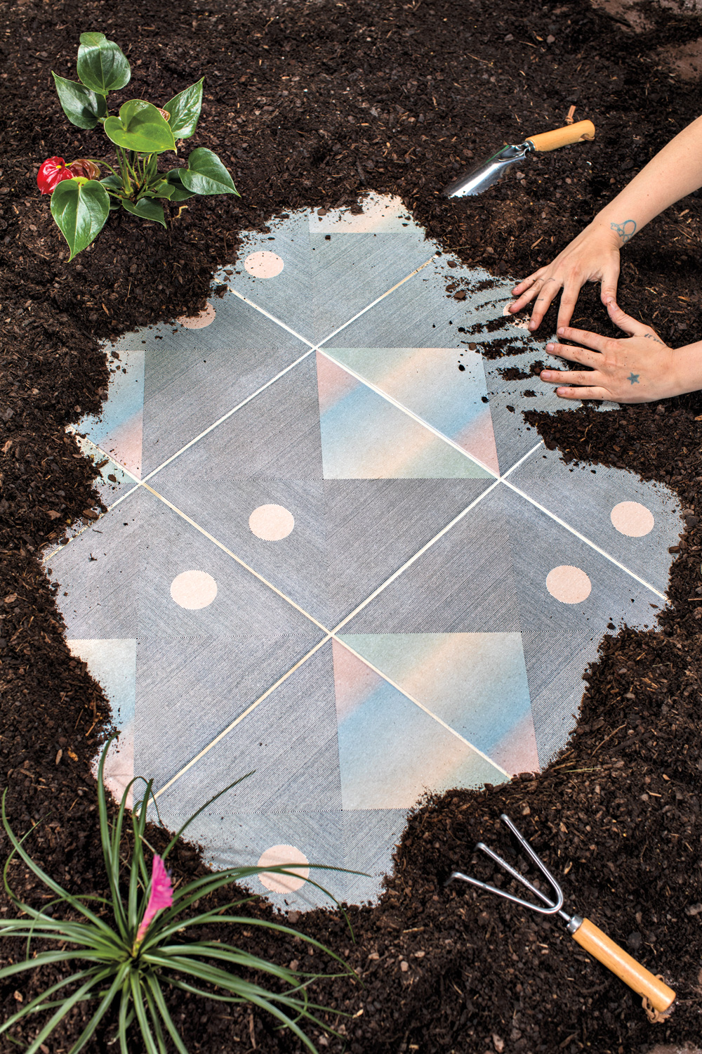 Haustile x Real Fun, Wow! tiles with soft rainbow motif being uncovered in a garden bed