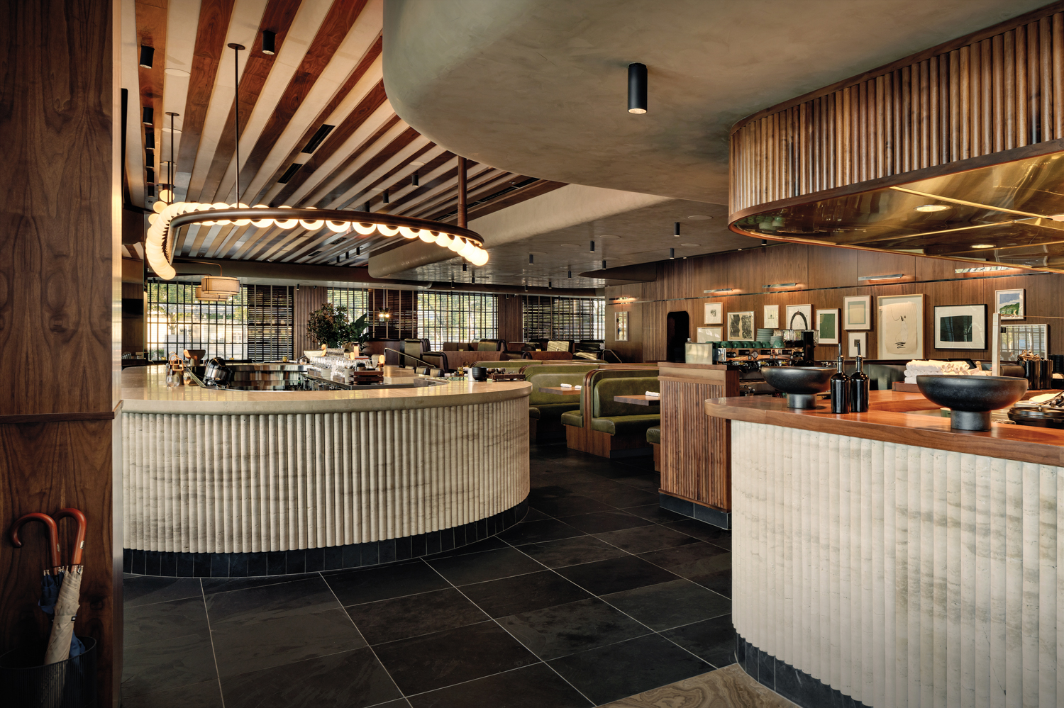 il Bracco restaurant dining space with slate and marble flooring, two white-ribbed bars and curated art hanging on wood-paneled walls