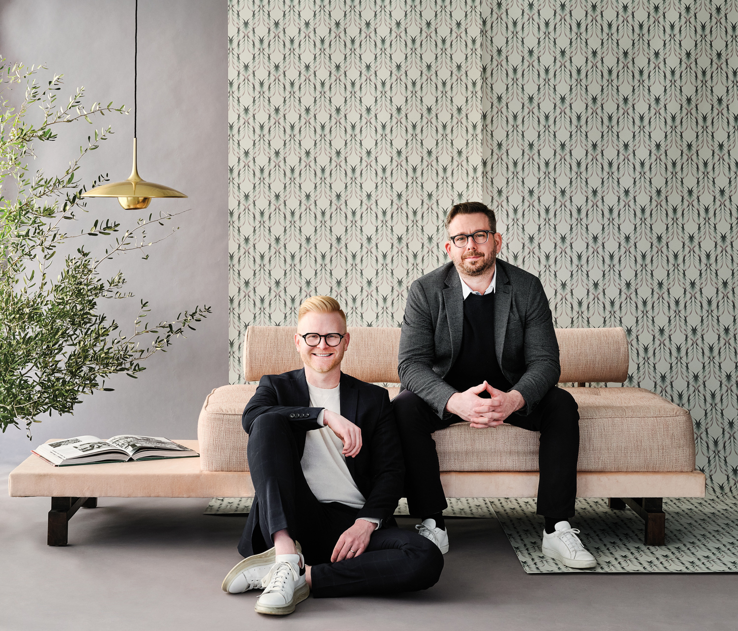 Bryan Yates and Mike Yates of Yates Desygn sit in front of a patterned wallpaper backdrop