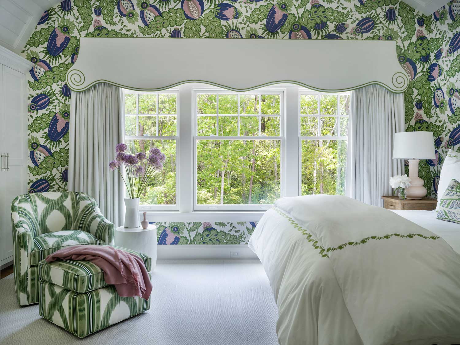 bedroom with green patterned window treatments and matching ottoman