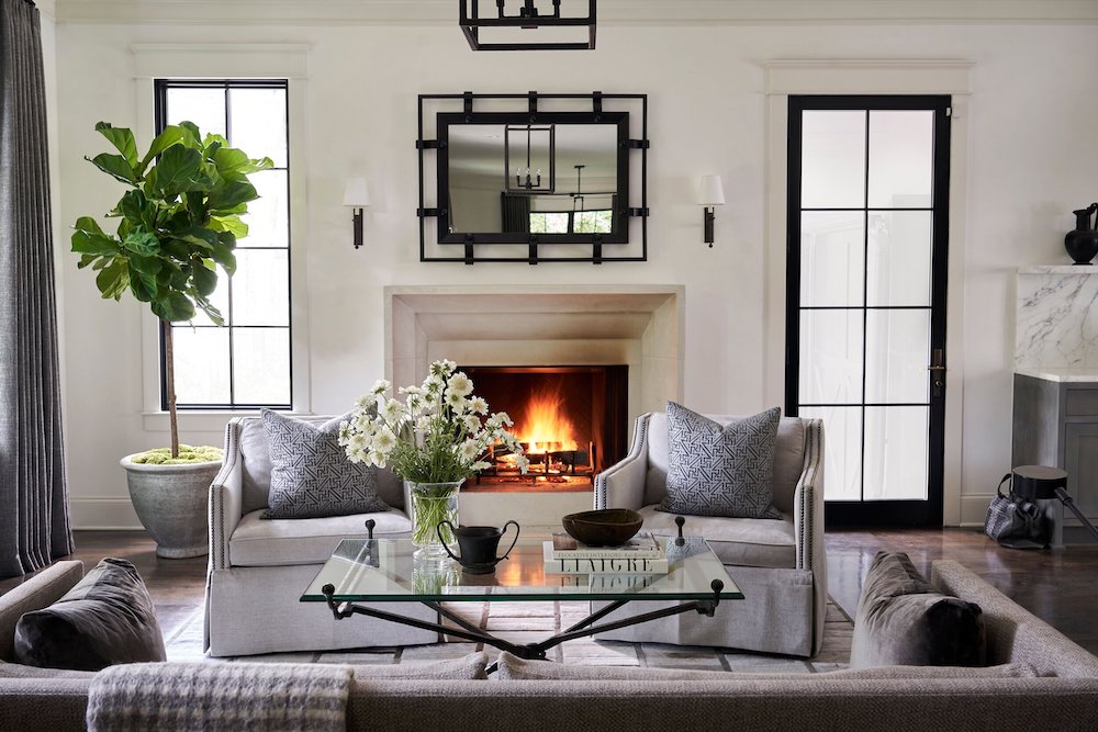 black framed windows add natural lighting to this neutral living room with fireplace and neutral colored seating