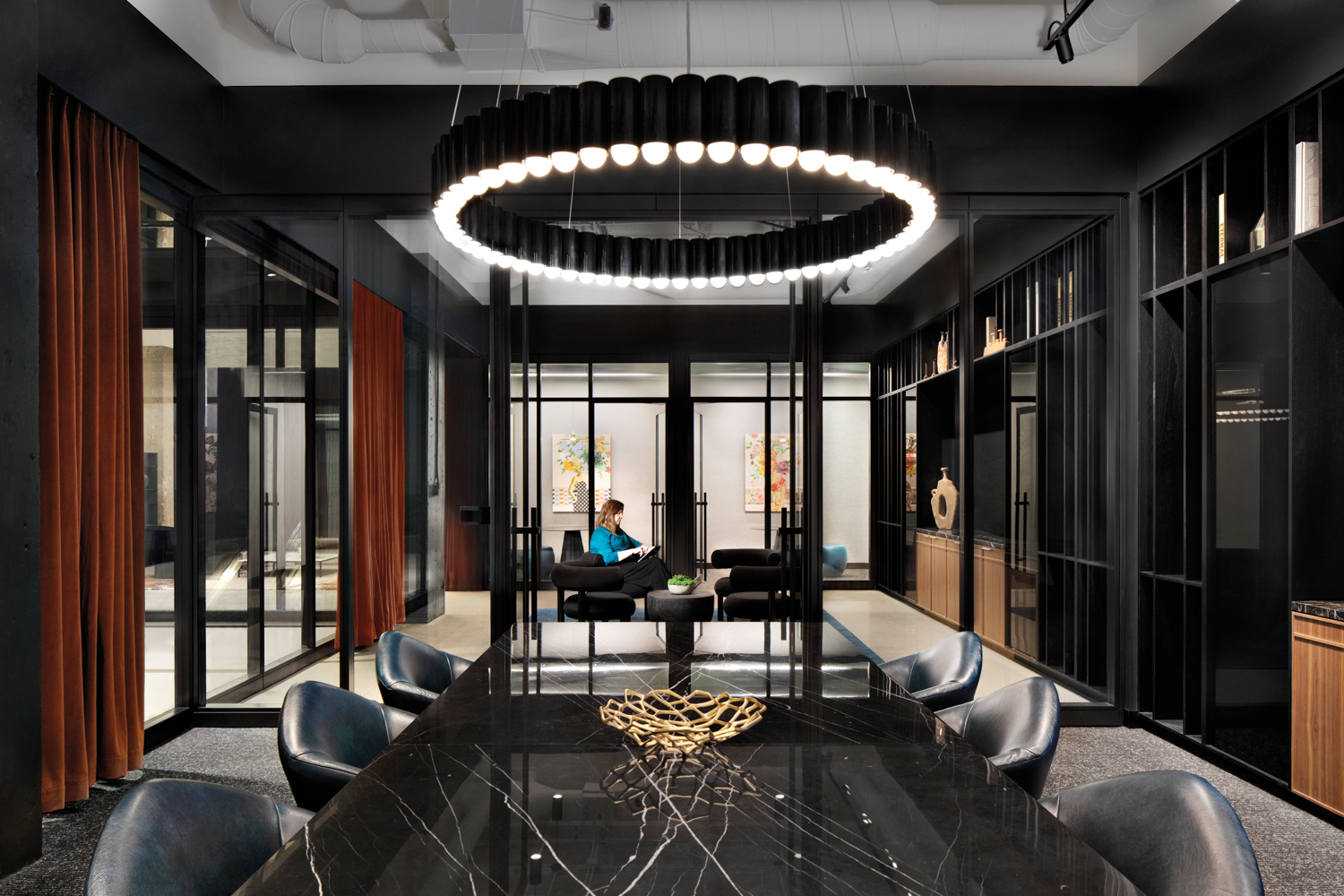 The Mart conference room with black stone table, black leather chairs and a circular chandelier