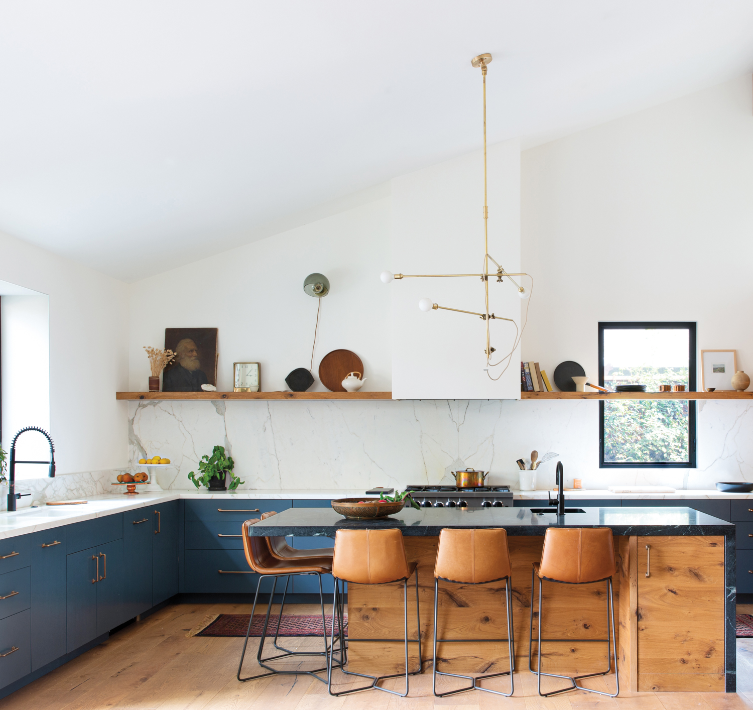 open kitchen with tan stools, kitchen island, blue cabinets and hanging asymmetrical light fixture