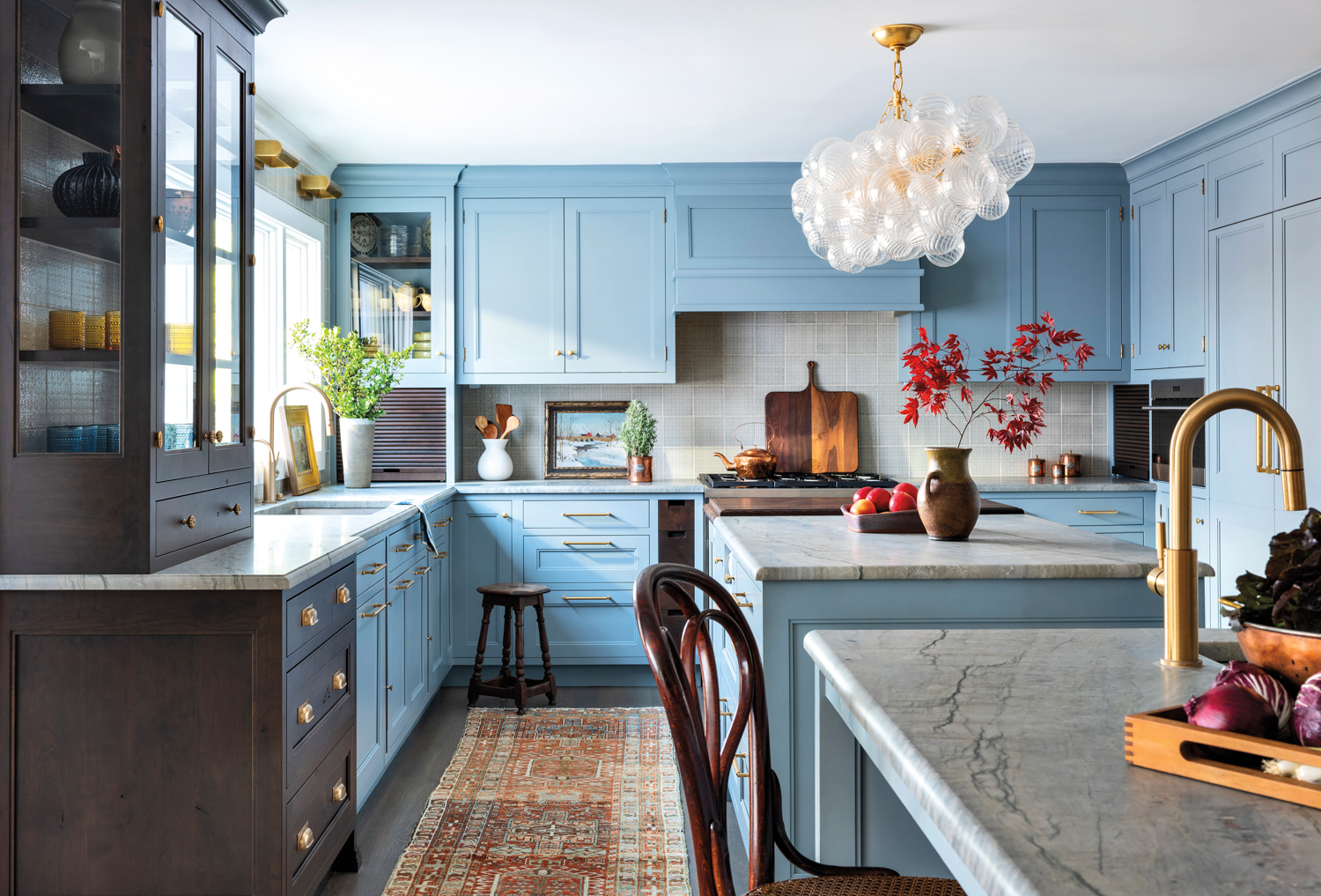 blue kitchen with quartzite countertops and circular bubble light fixture