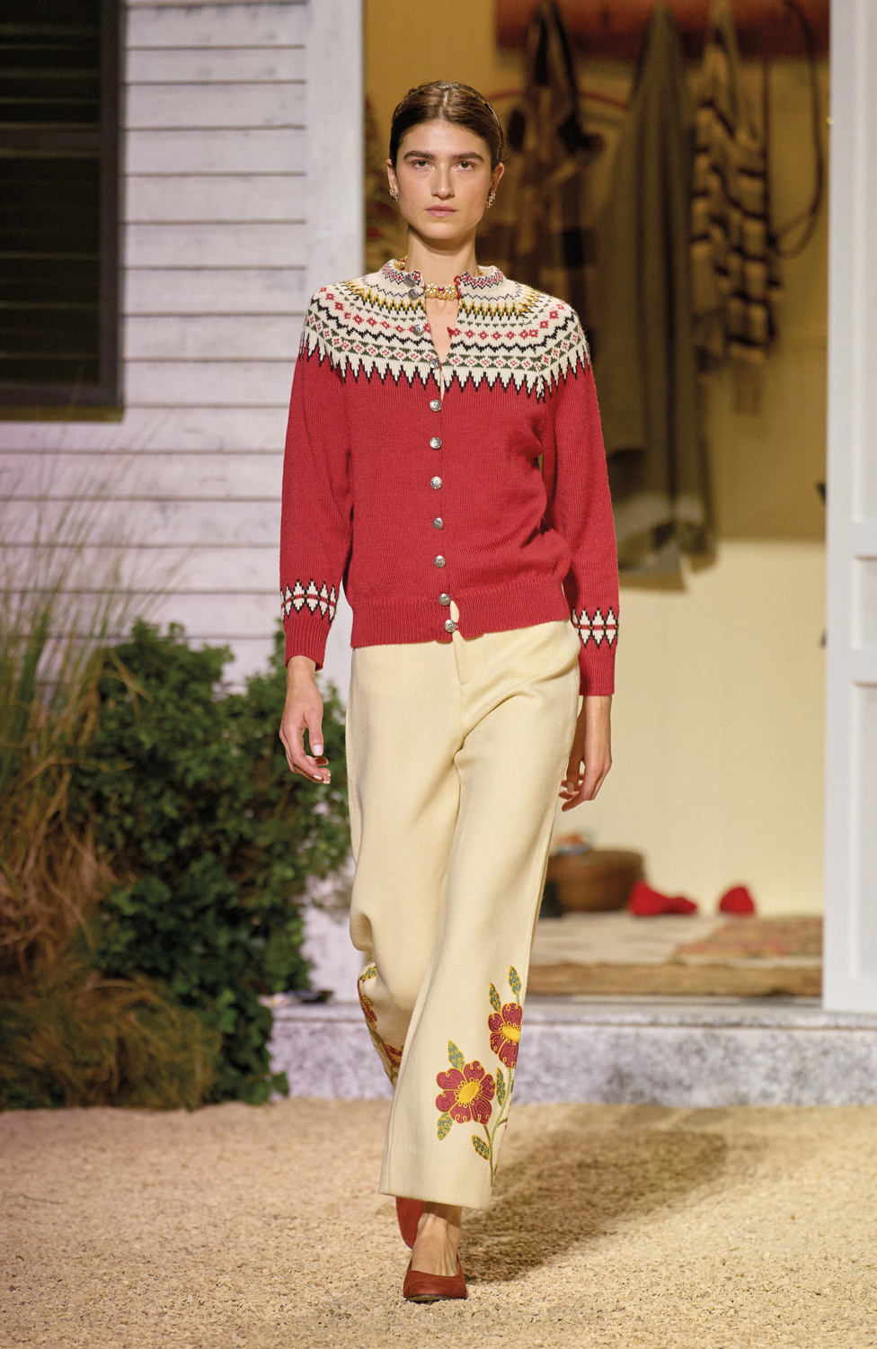 woman in front of house wearing red top and beige pants