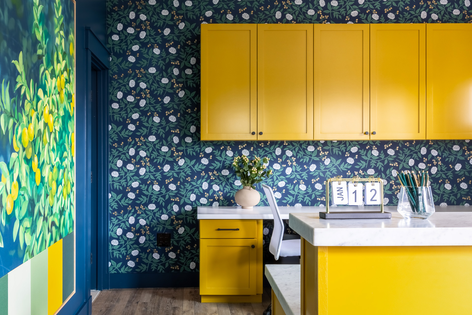 a mustard yellow by sherwin williams accents cabinetry in a blue office with floral wallpaper