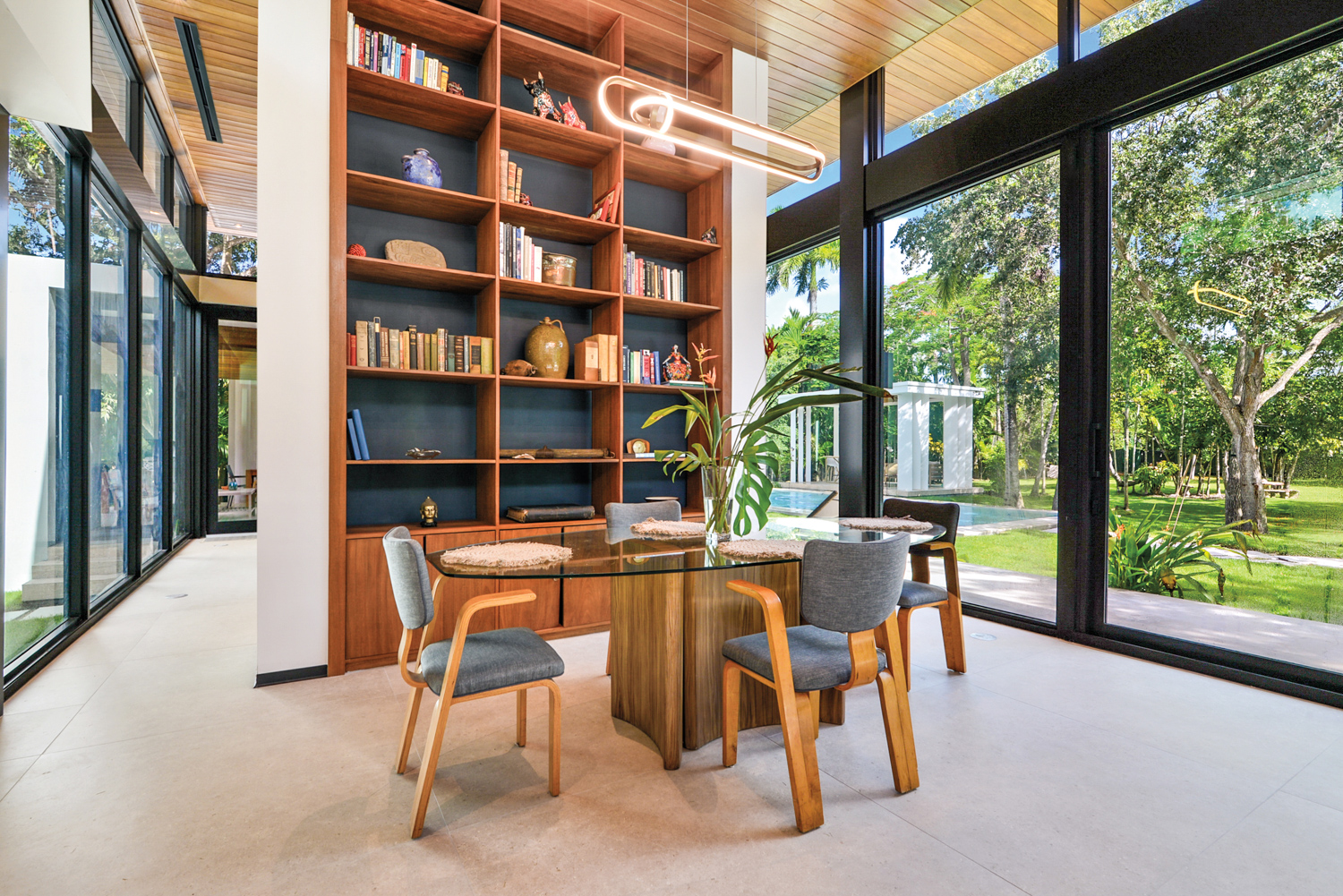 Floor-to-ceiling built-in wood bookcases by Simpatco Architectural Surfaces center a dining space