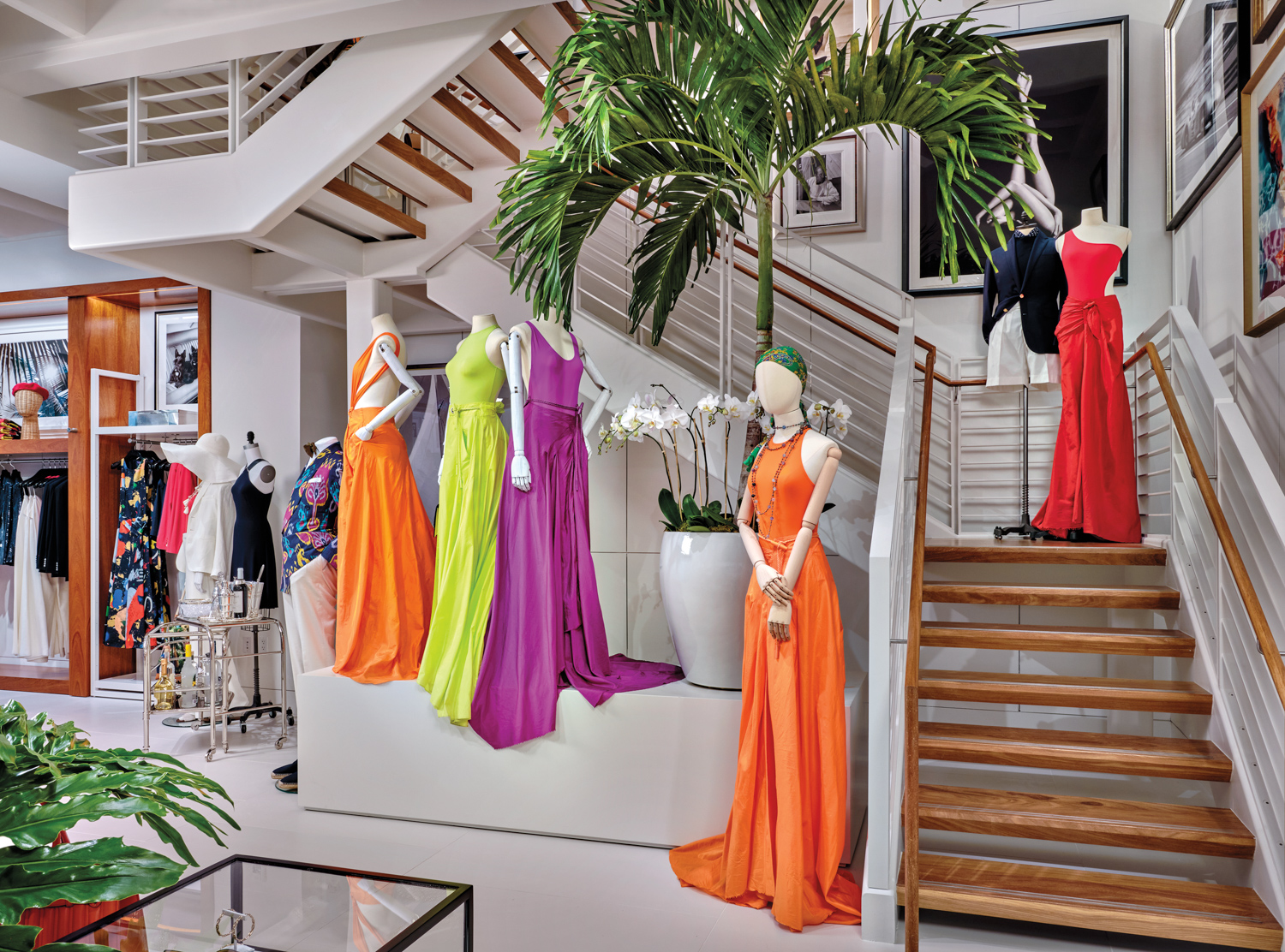 Mannequins wear vibrant dresses along staircase of warm teak wood planks and crisp-white tile flooring.