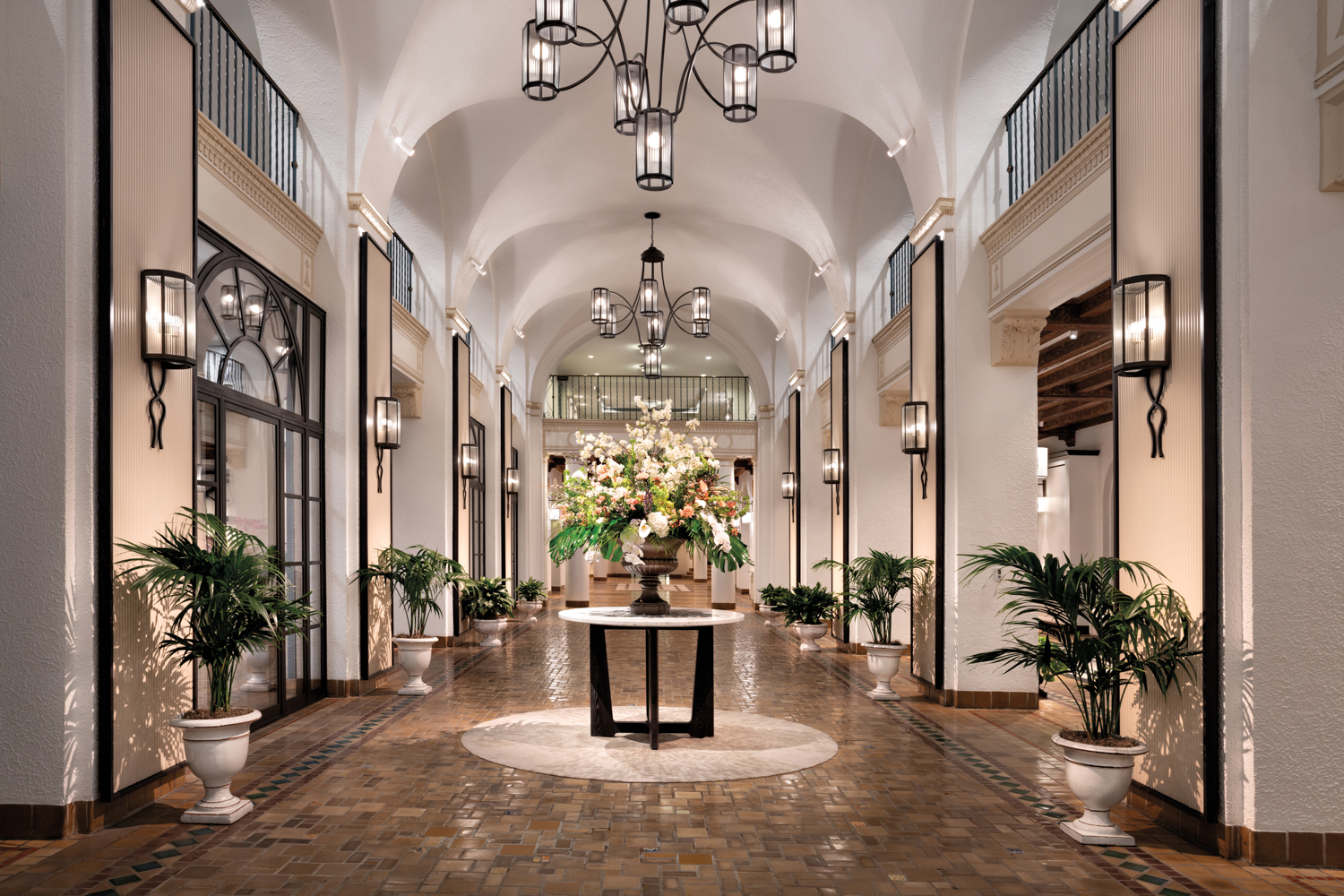 Ceramic floor, cypress beams and pilasters line a lobby studded with sconces and chandeliers