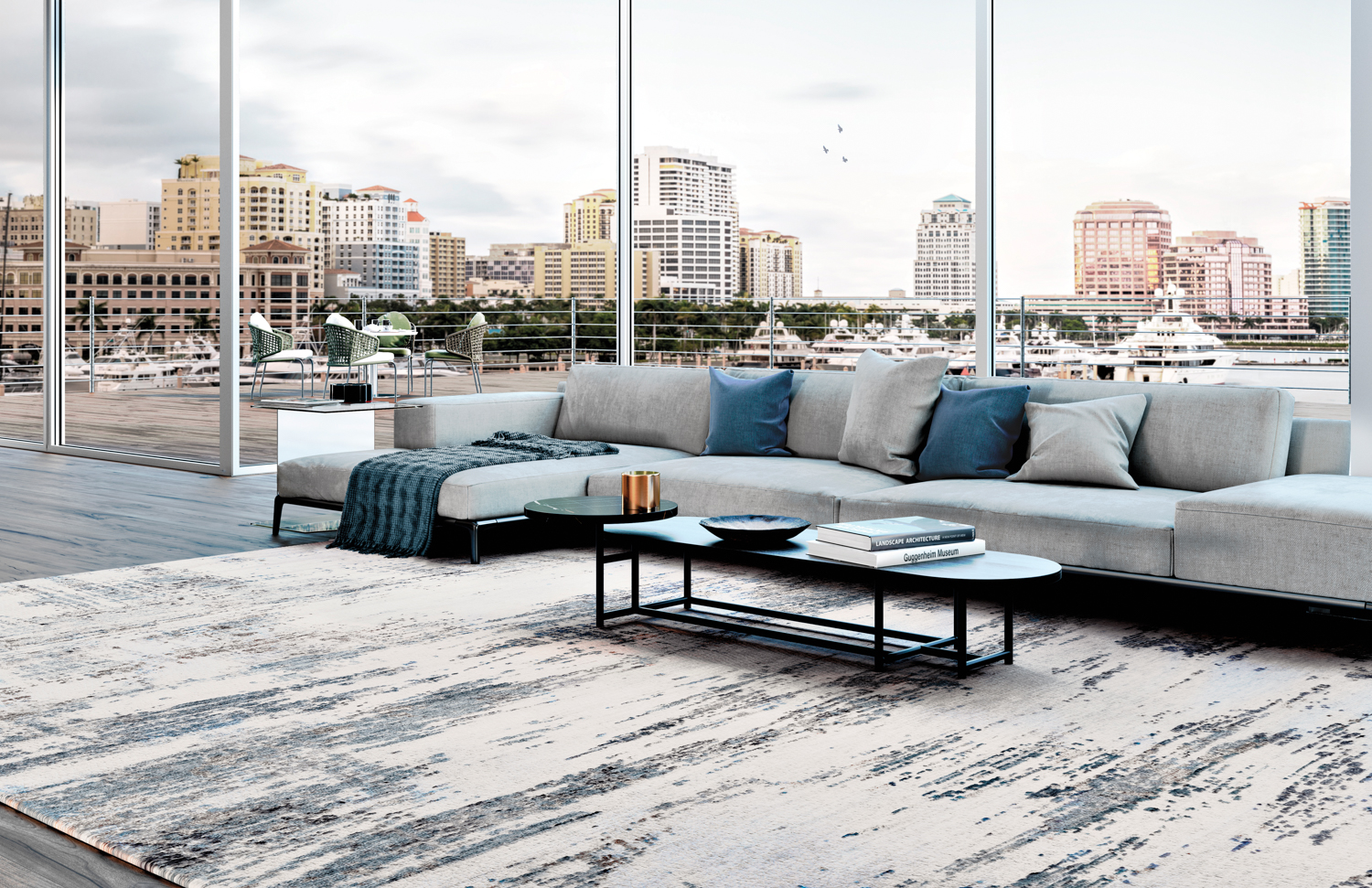 Floor-to-ceiling windows back a large gray sectional on large cream-and-blue area rug in Stark Naples showroom
