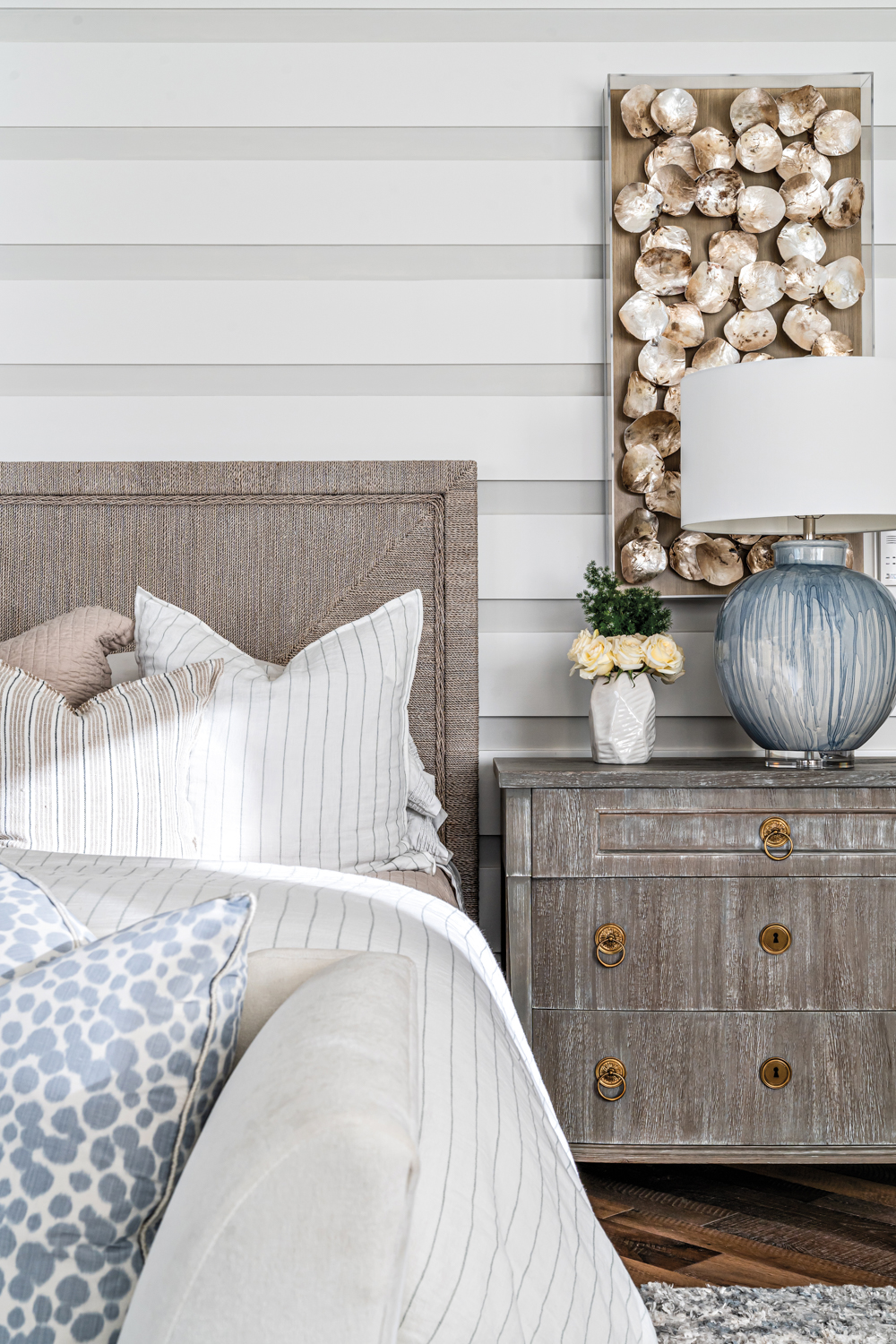Neutral-toned bedroom vignette and wooden nightstand in Design West showroom
