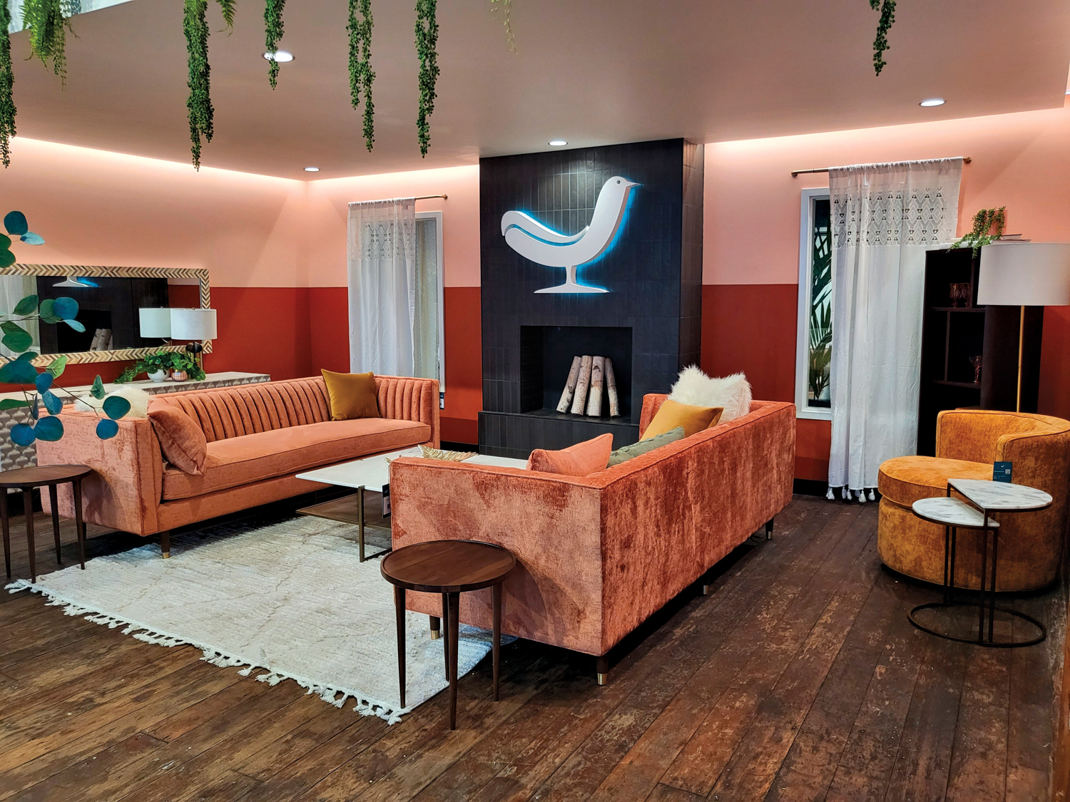 Showroom with coral-colored tufted sofas, pink and red walls and a black tile-clad fireplace