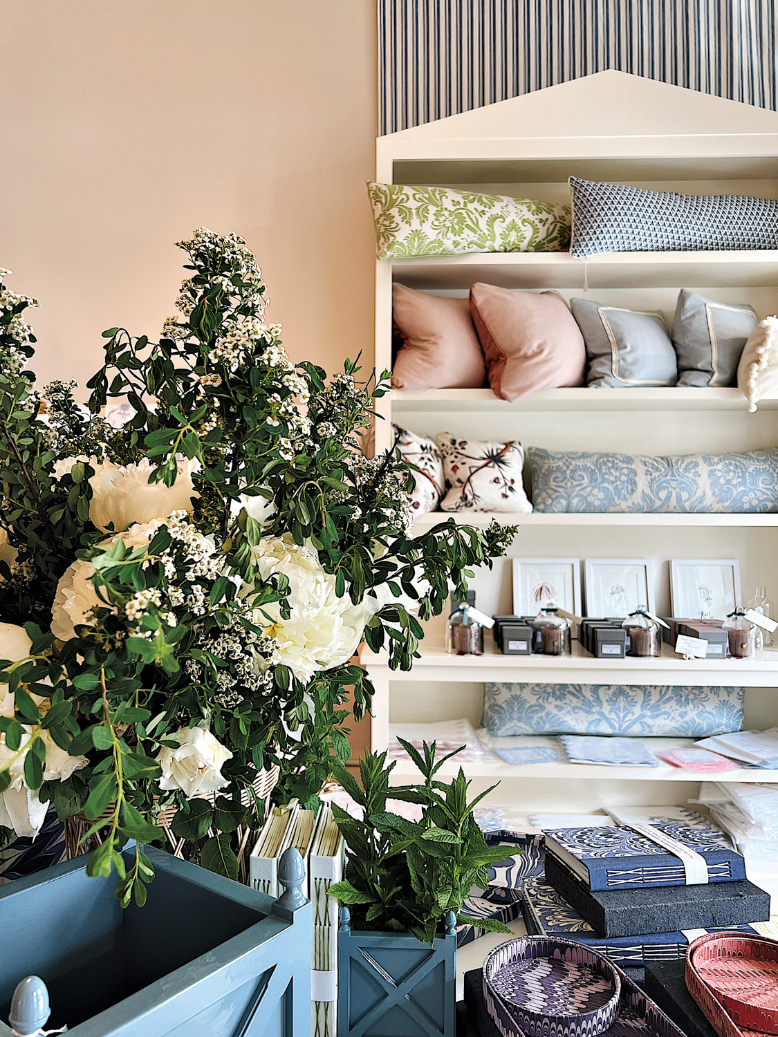 Home decor shop by Josephine Fisher Freckmann with a white shelf full of decorative pillows