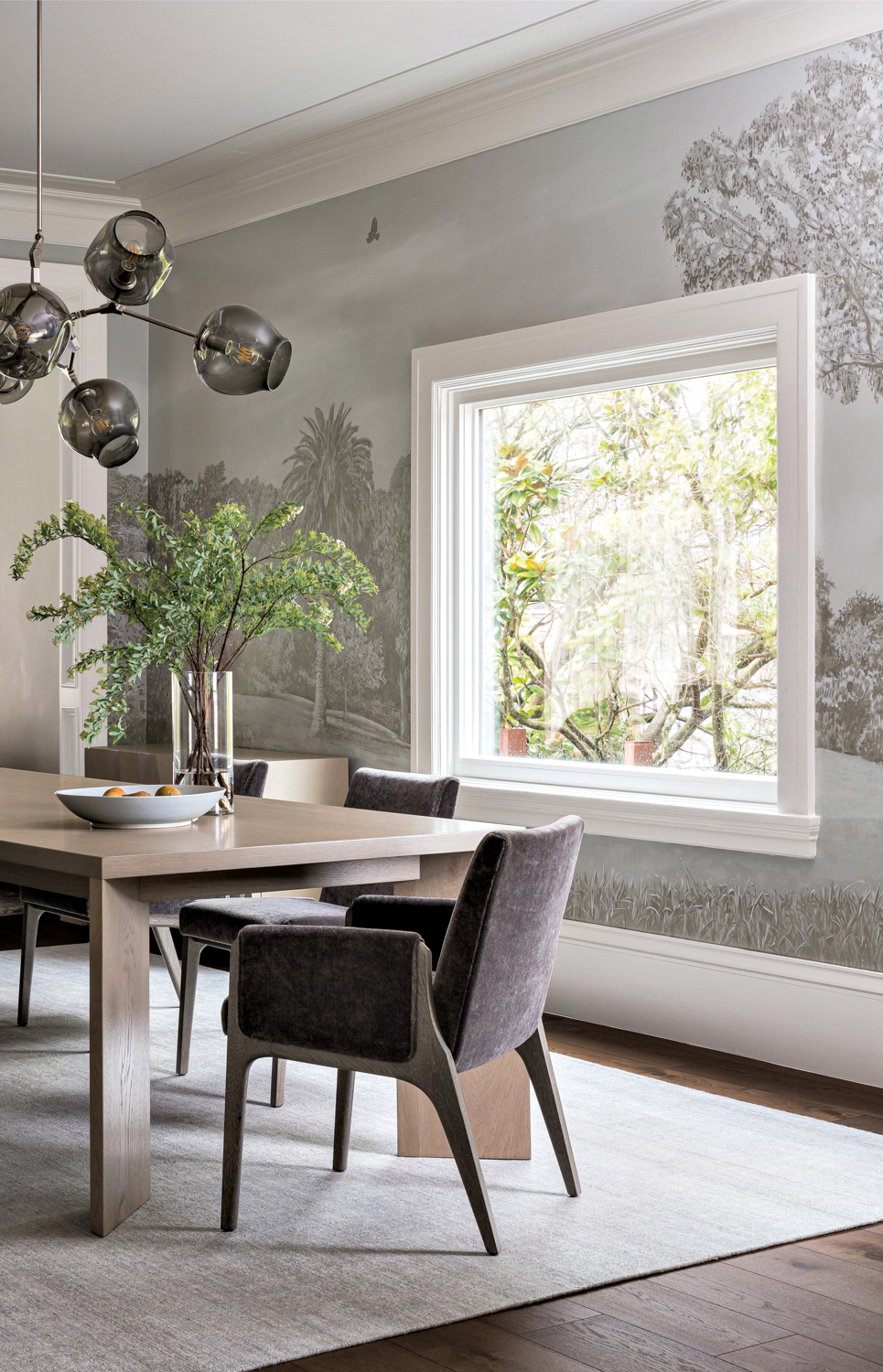 Dining room with landscape mural by Charles Leonard on the walls, wood table and dark, upholstered chairs