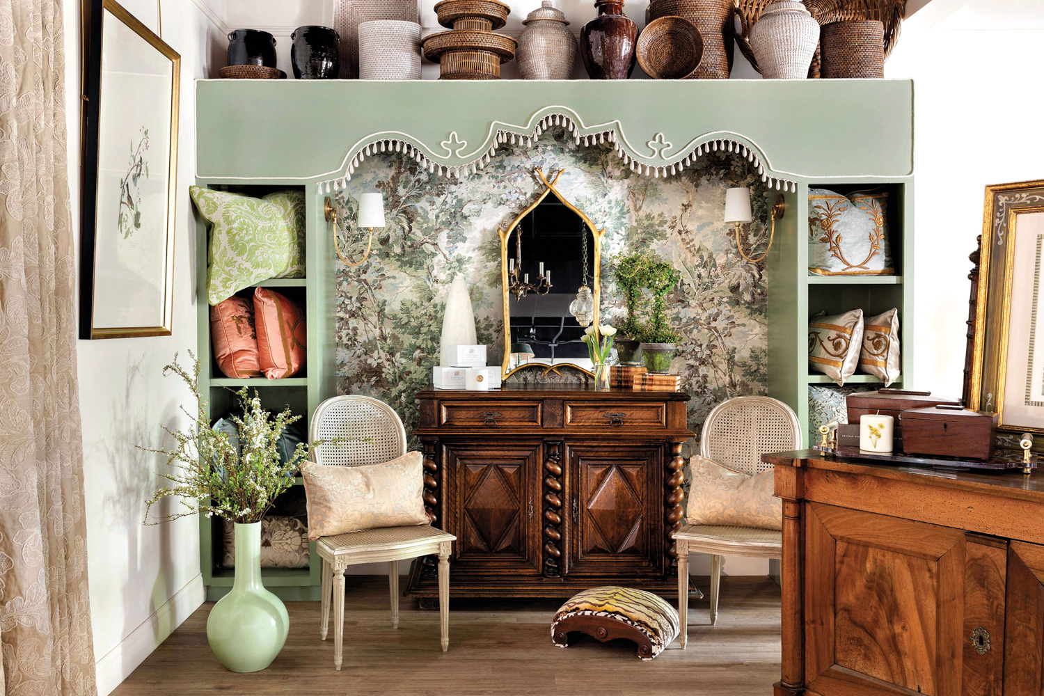 A dark-wood console sits in an alcove in a leafy-patterned wallpaper framed by built-in shelves by Debbie Mathews
