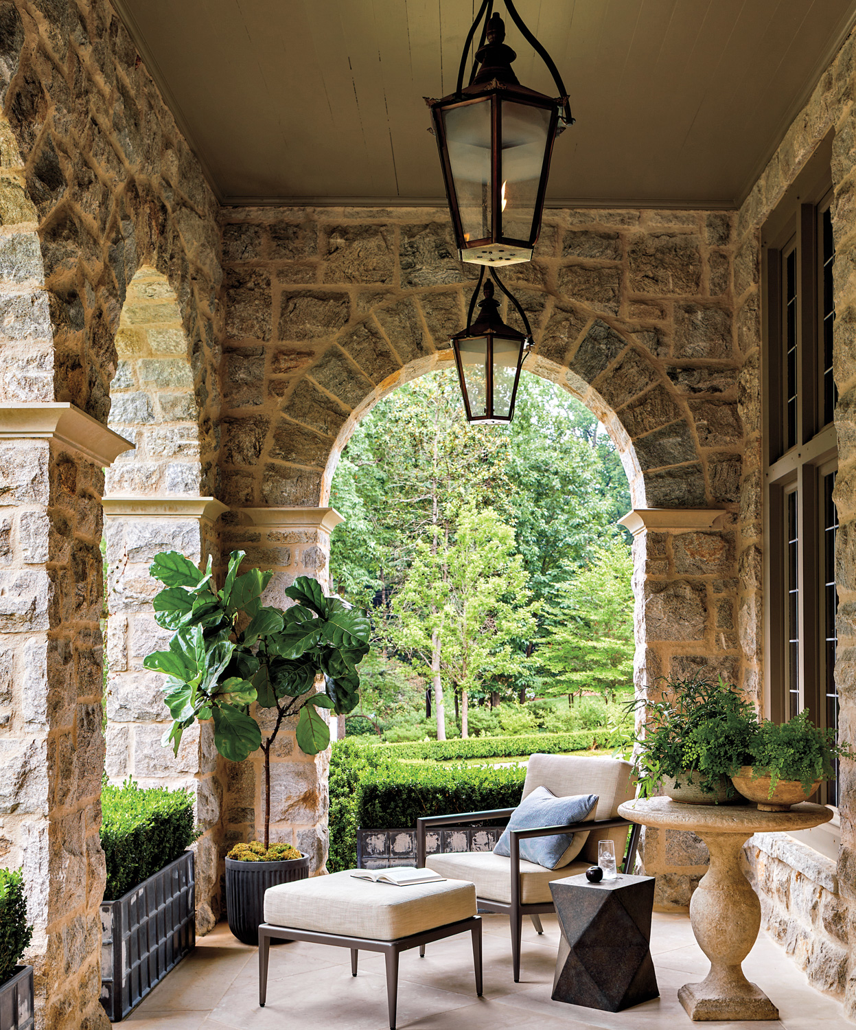 Covered patio seating area with stone archways and 2 pendant light fixtures by Stan Dixon