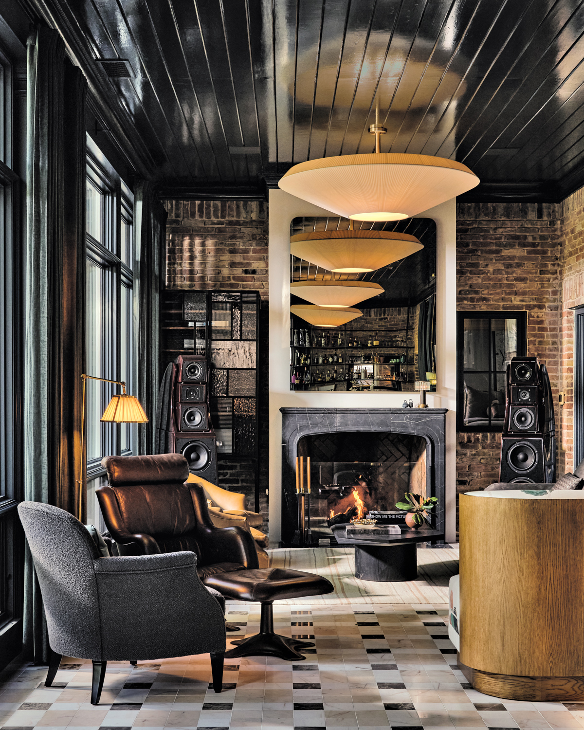 Large, stacked speakers flank fireplace in casual seating area with exposed brick chosen by Chad Dorsey Design