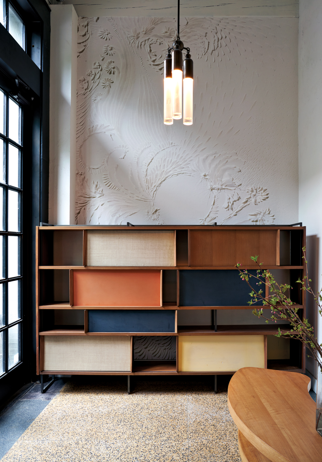 Midcentury modern-style console against white-plastered walls with a light fixture handing at center