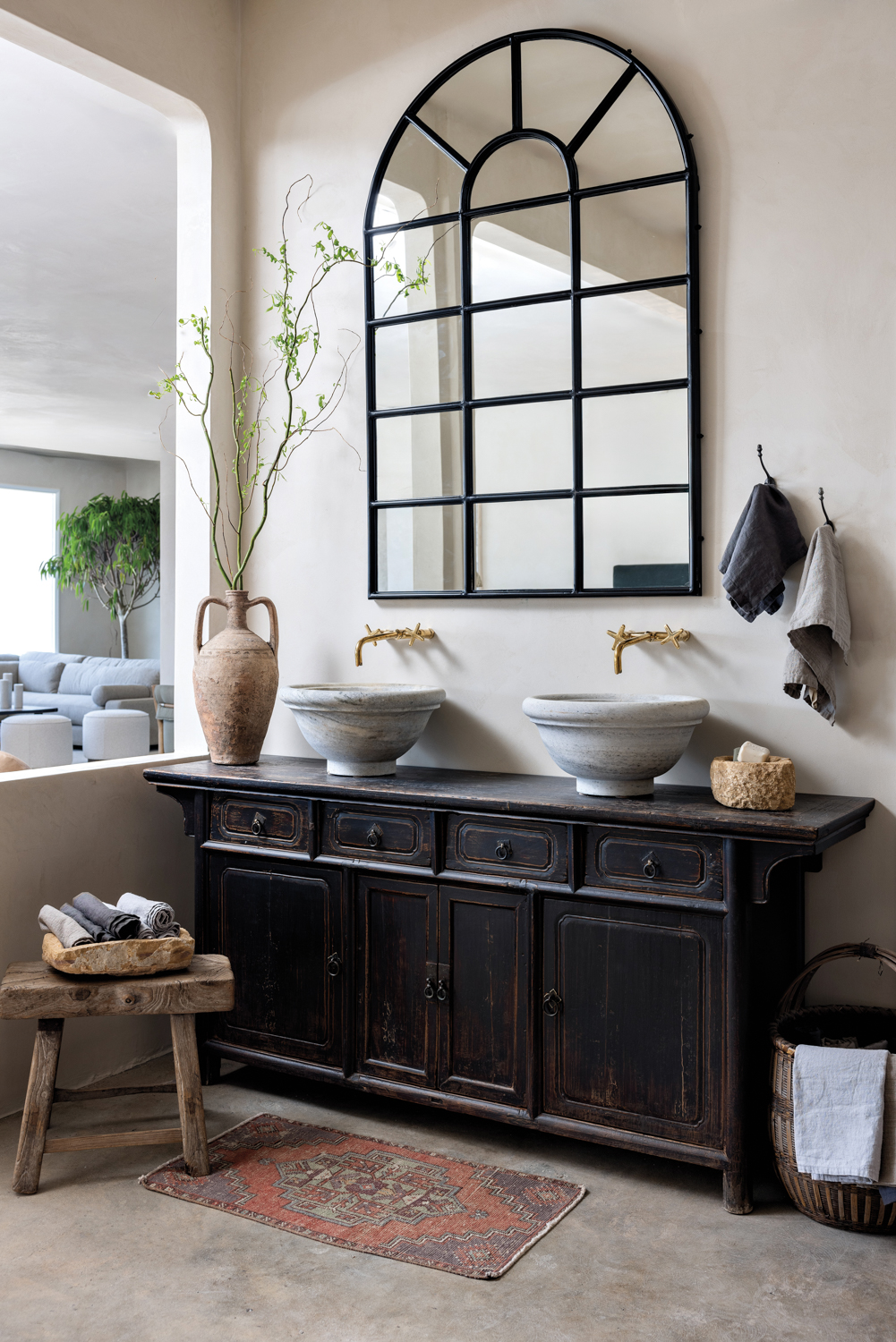 A black dresser with a window-shaped mirror hanging above it and vessels resting on top in Habitat Home & Garden