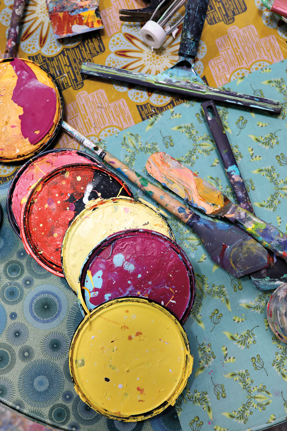 a curved line of artist's paint lids and various paint splattered tool