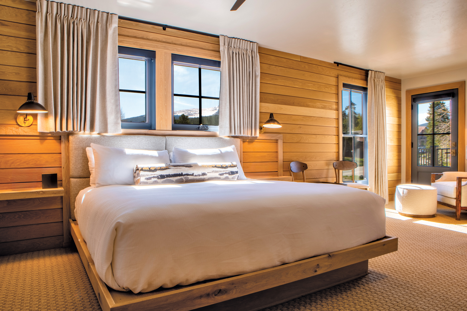 Hotel room with wood-plank walls and a bed and bedroom furniture in neutral hues