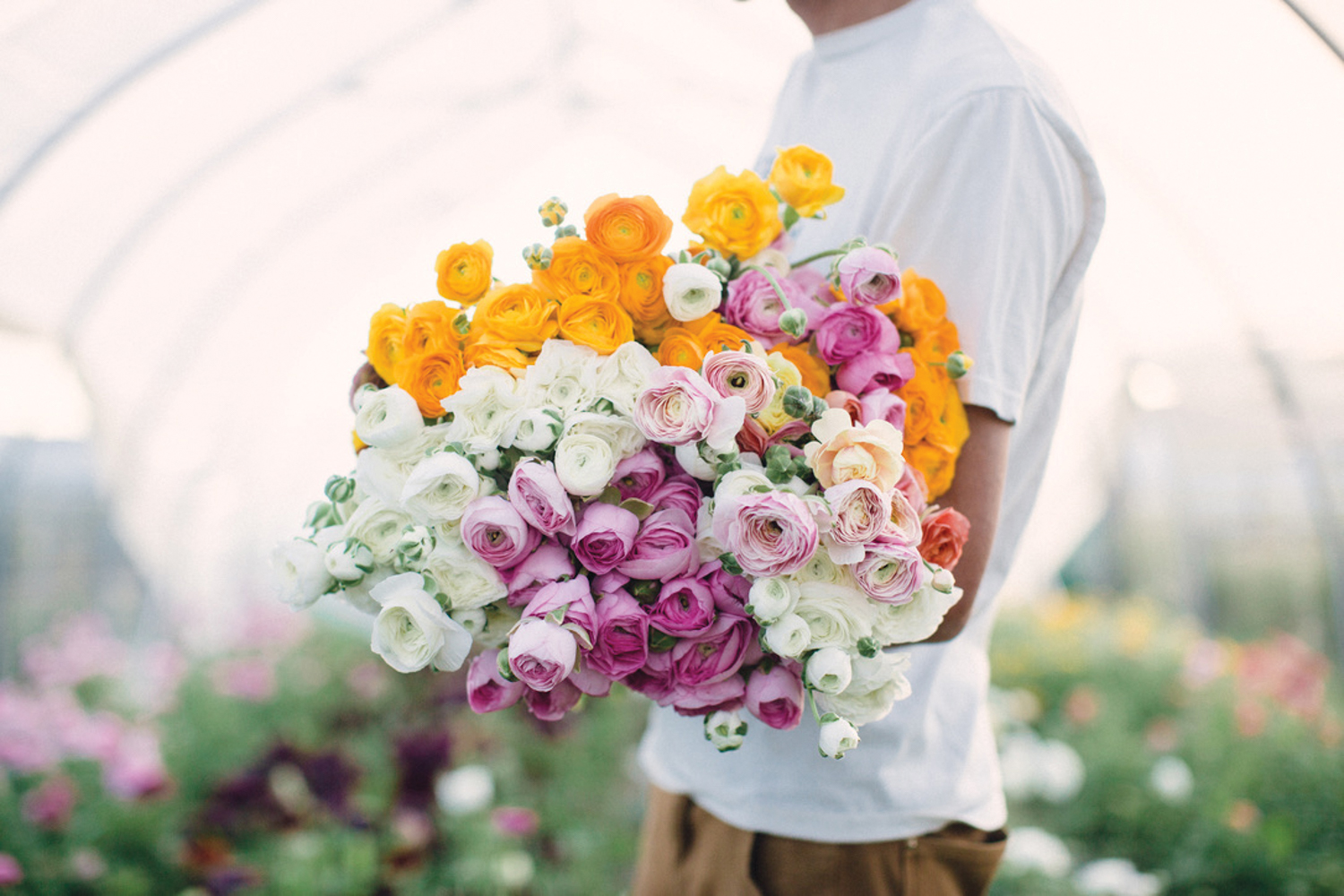 Man in a white shirt holding a bouquet of orange, white and pink flowers