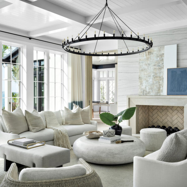 living room with white sofas, round stone coffee table, gray wall, fireplace and round black chandelier