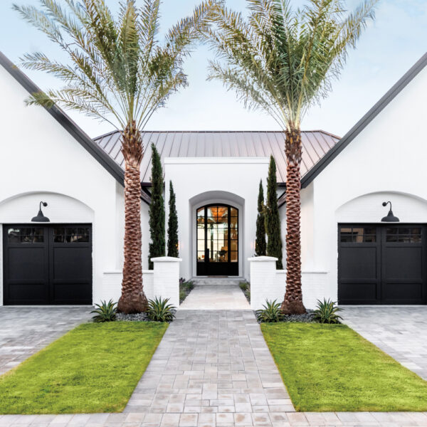 front exterior of white home by Kelsey McGregor with two black garage doors and two palm trees